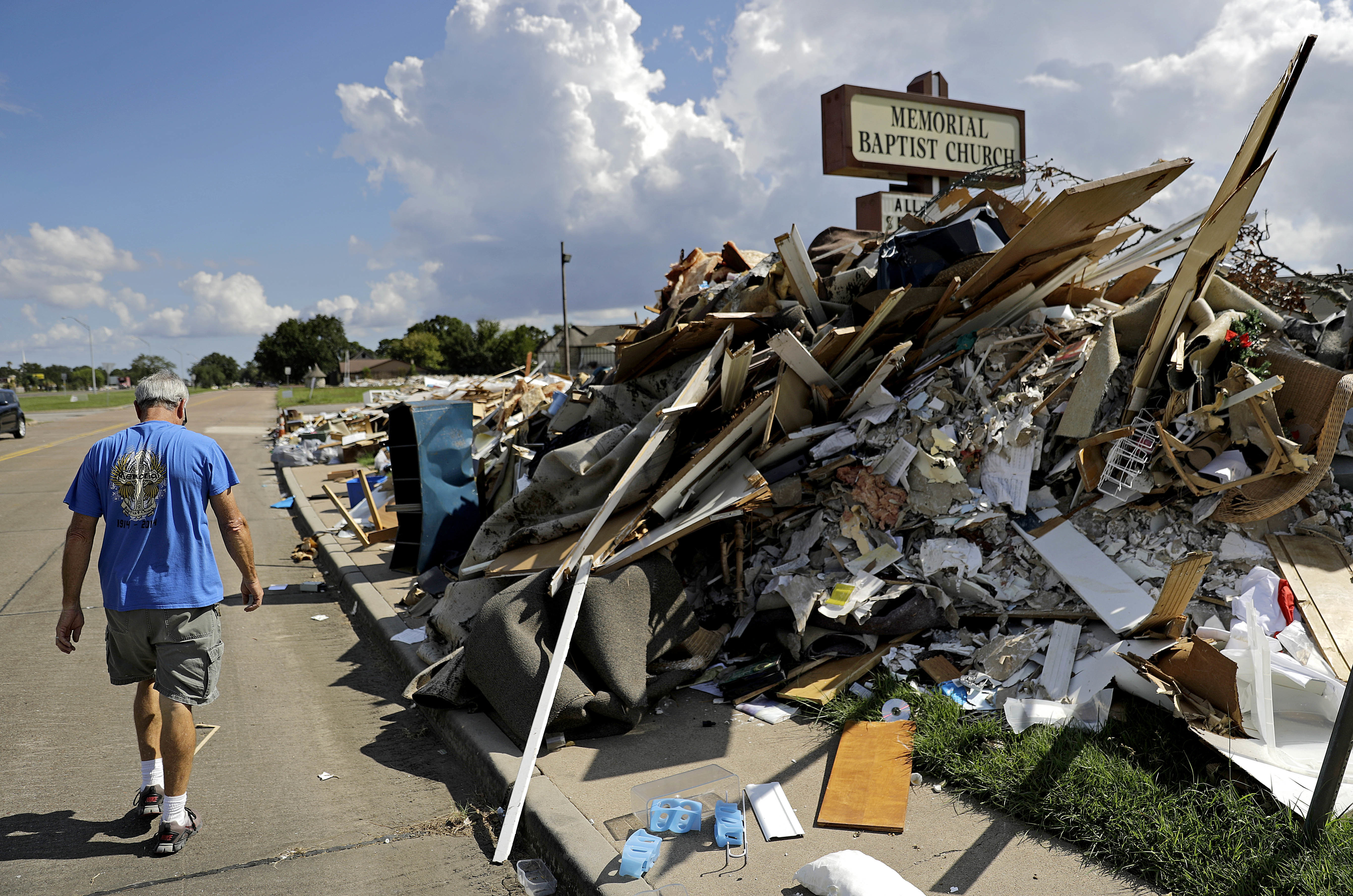Wayne Christopher walks by a pile of debris outside the church he'd attended his whole life damaged from Hurricane Harvey in Port Arthur, Texas, Monday, Sept. 25, 2017. CREDIT: AP Photo/David Goldman