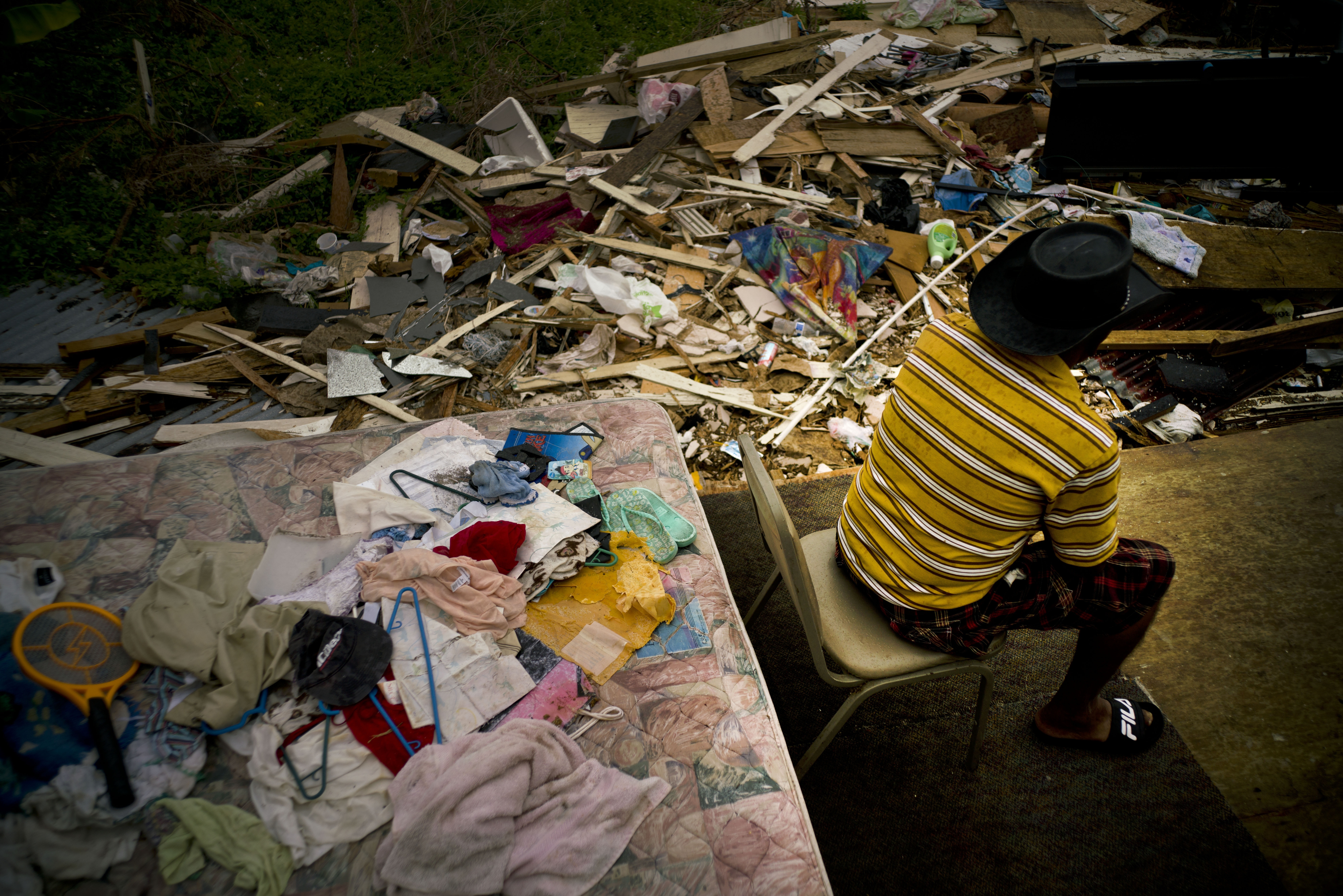 Efrain Diaz Figueroa spends the afternoon sitting on a chair next to the remains of the house of his sister destroyed by Hurricane Maria in San Juan, Puerto Rico, Monday, Oct. 9, 2017. CREDIT: AP Photo/Ramon Espinosa