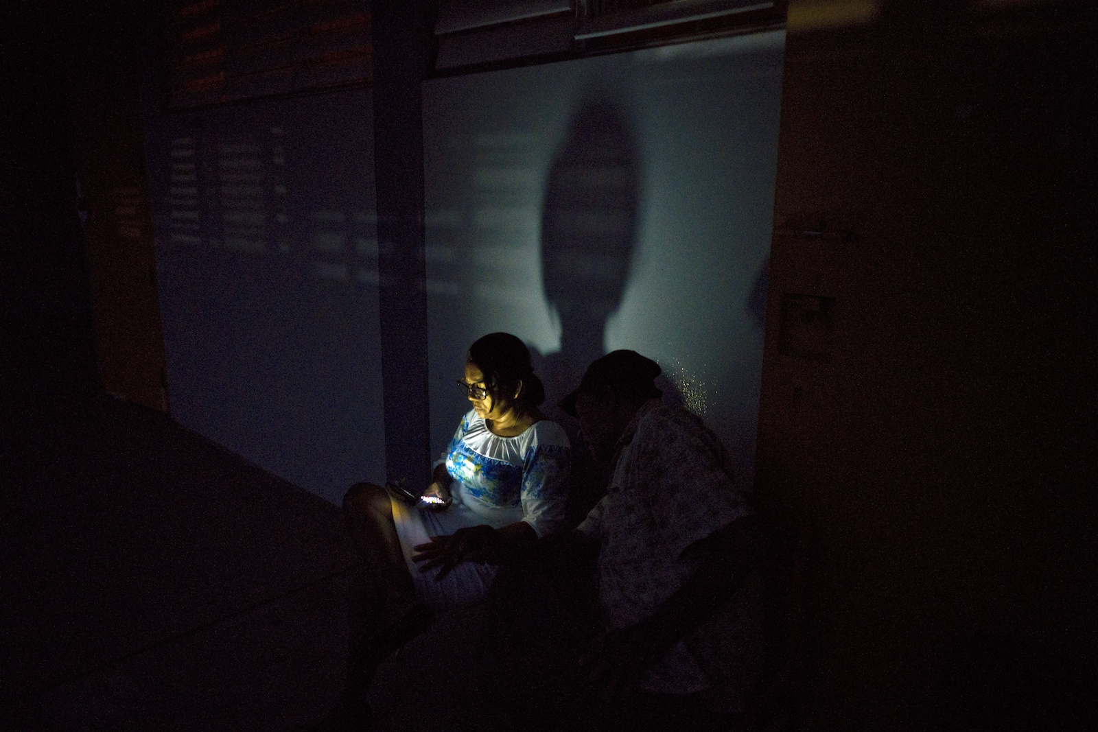 A woman left homeless by Hurricane Maria uses her cell phone at a school-turned-shelter that does not have electricity in Toa Baja, Puerto Rico, Thursday, October 12. Days later, the island actually had less power. CREDIT: AP/Ramon Espinosa.