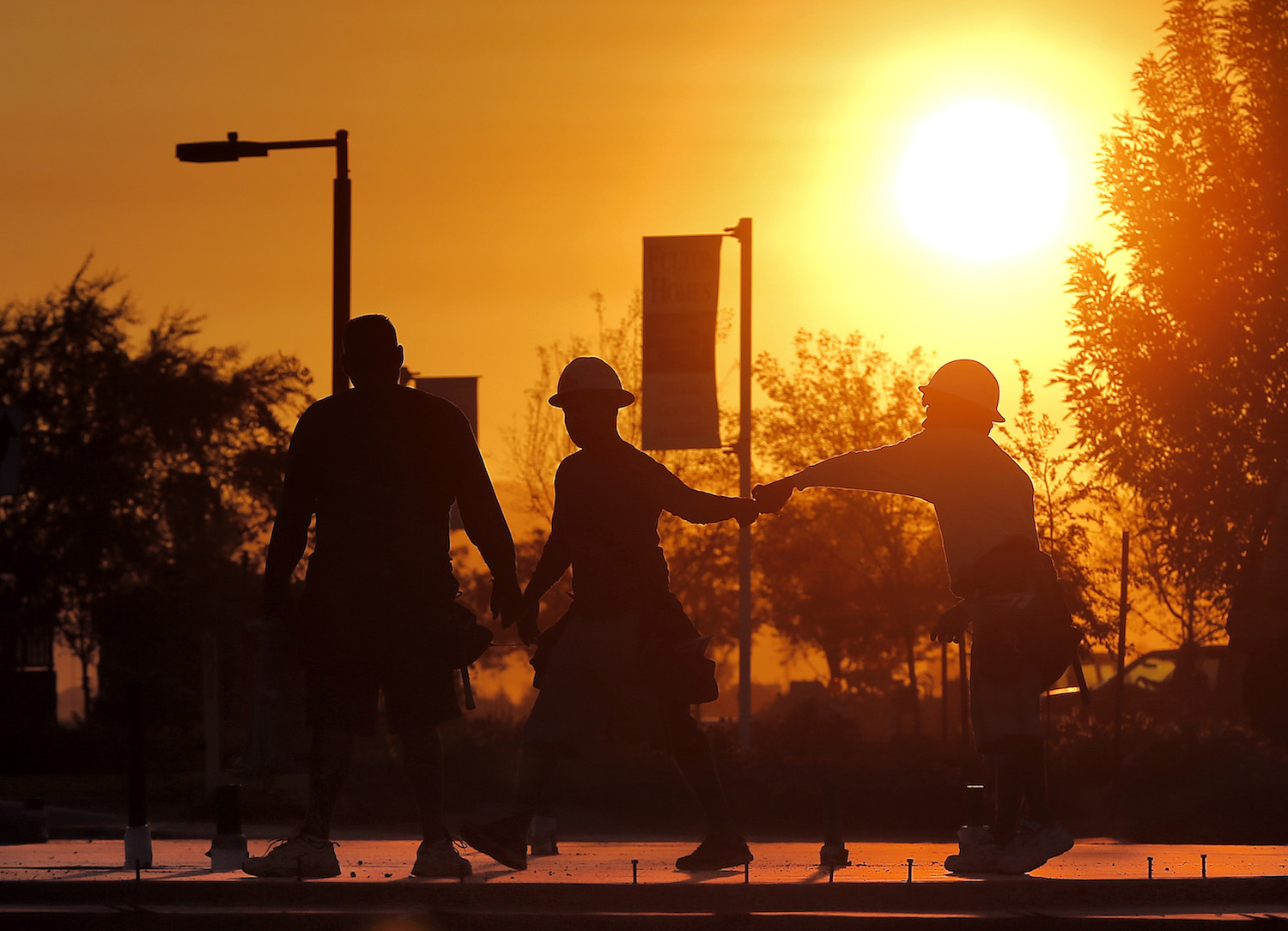 Workers gather at a new home site at sunrise to beat daytime high temperatures in Arizona exceeding 110 F, June 27, 2013. CREDIT: AP/Matt York