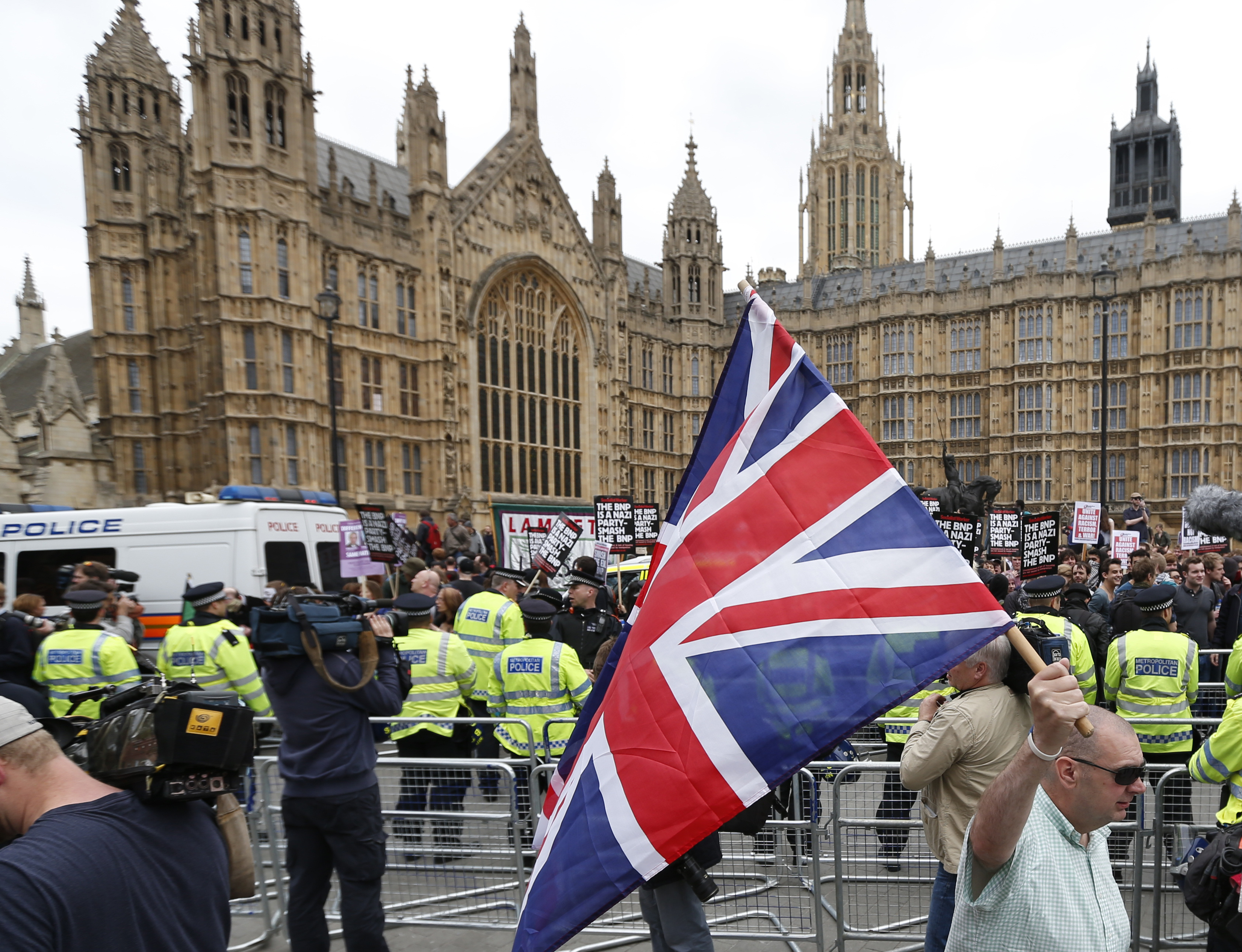 A member of the British National Party (BNP), holds a Union Jack during a demonstration as anti-fascist demonstrators, in the background, shout slogans in a counter demonstration in central London. (AP Photo/Lefteris Pitarakis)