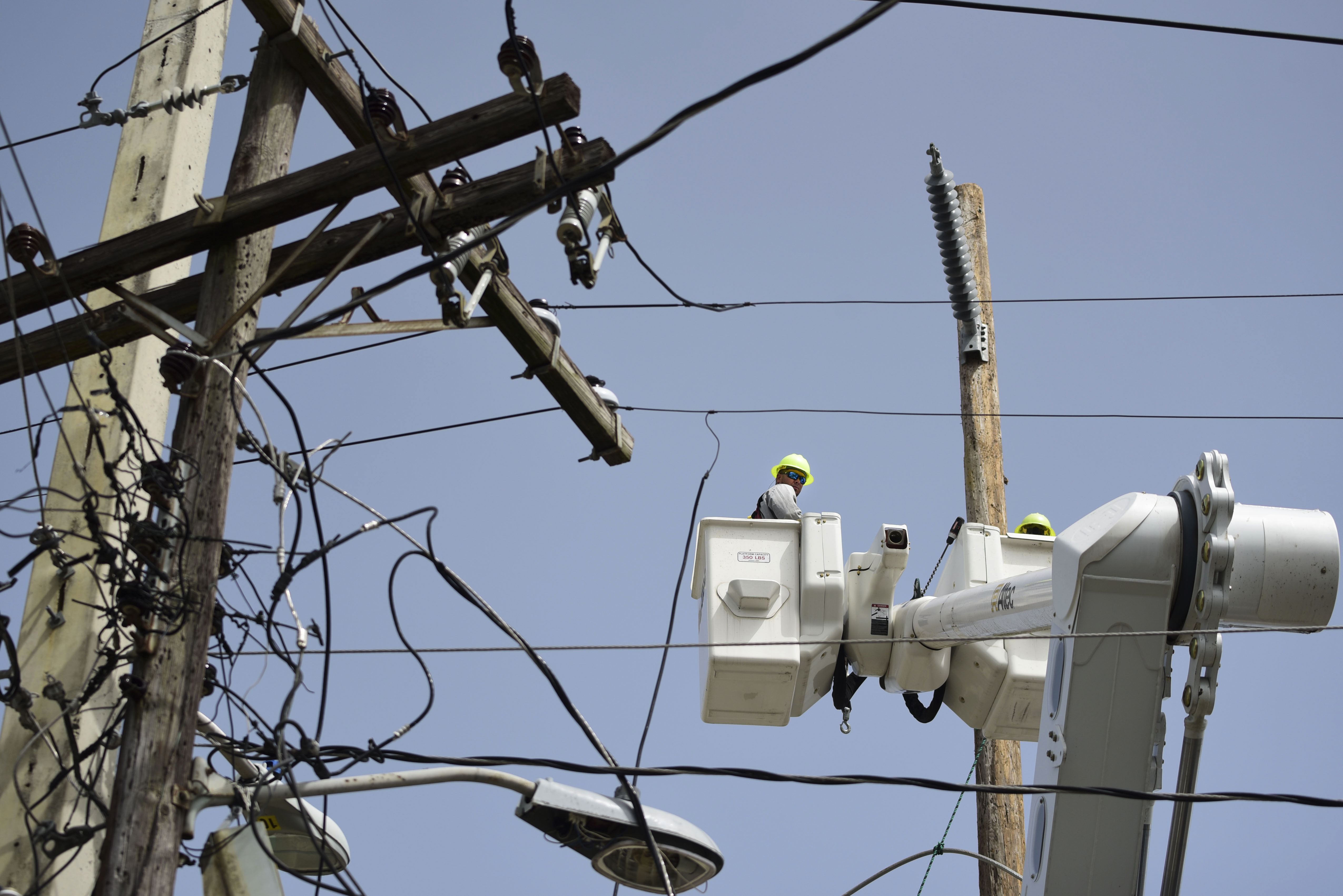 Workers seek to repair distribution lines damaged by Hurricane Maria in the Cantera community of San Juan, Puerto Rico. CREDIT: AP Photo/Carlos Giusti