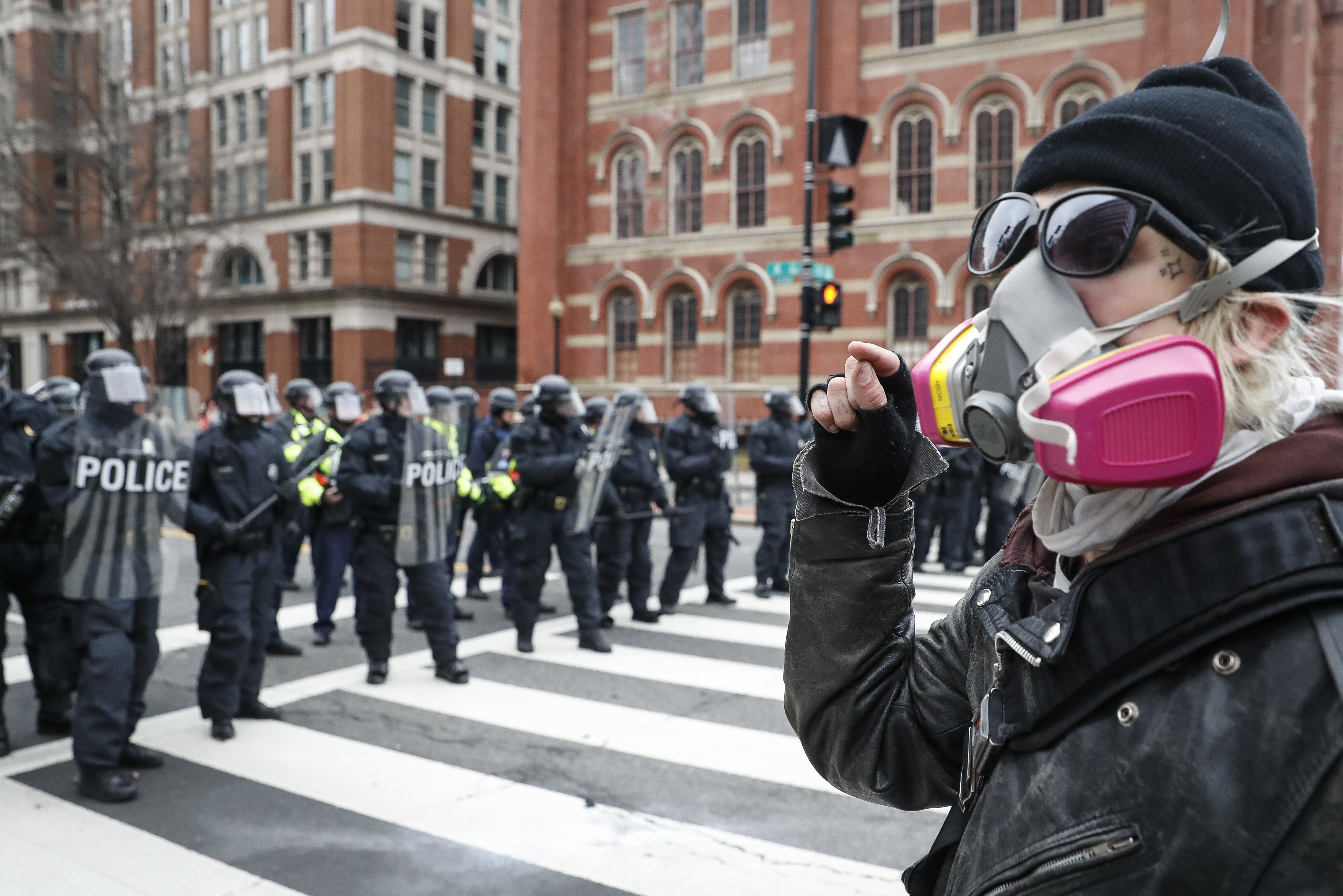 A protester faces off with a line of riot police during a demonstration on Inauguration Day that has since led to hundreds of people facing felony charges for rioting. CREDIT: AP Photo/John Minchillo