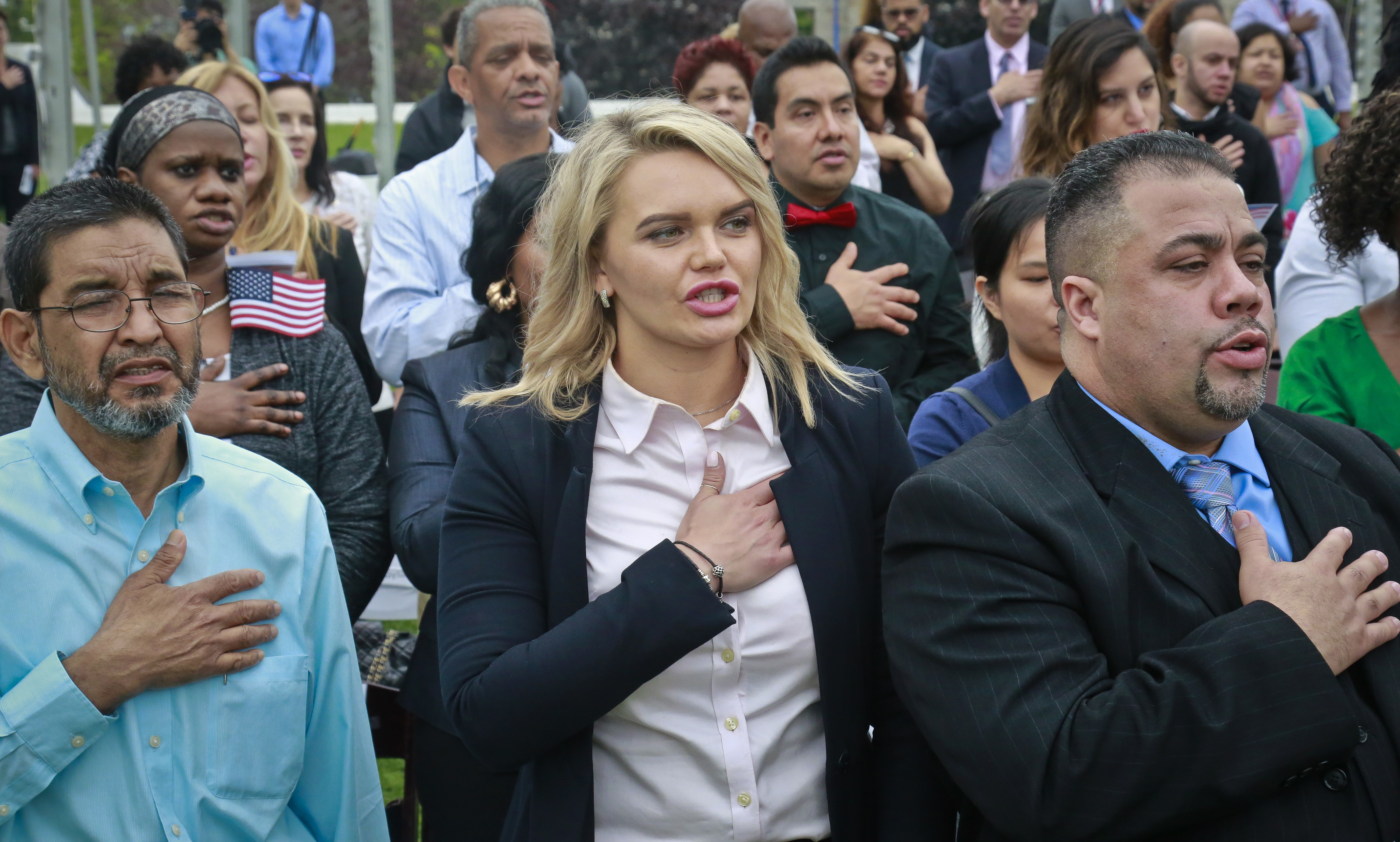 Immigrants among fifty from twenty four countries, raise hands to chest as the National Anthem played during the U.S. Citizen and Immigration Services (USCIS) naturalization ceremony, Friday June 16, 2017, in New York. CREDIT: AP Photo/Bebeto Matthews