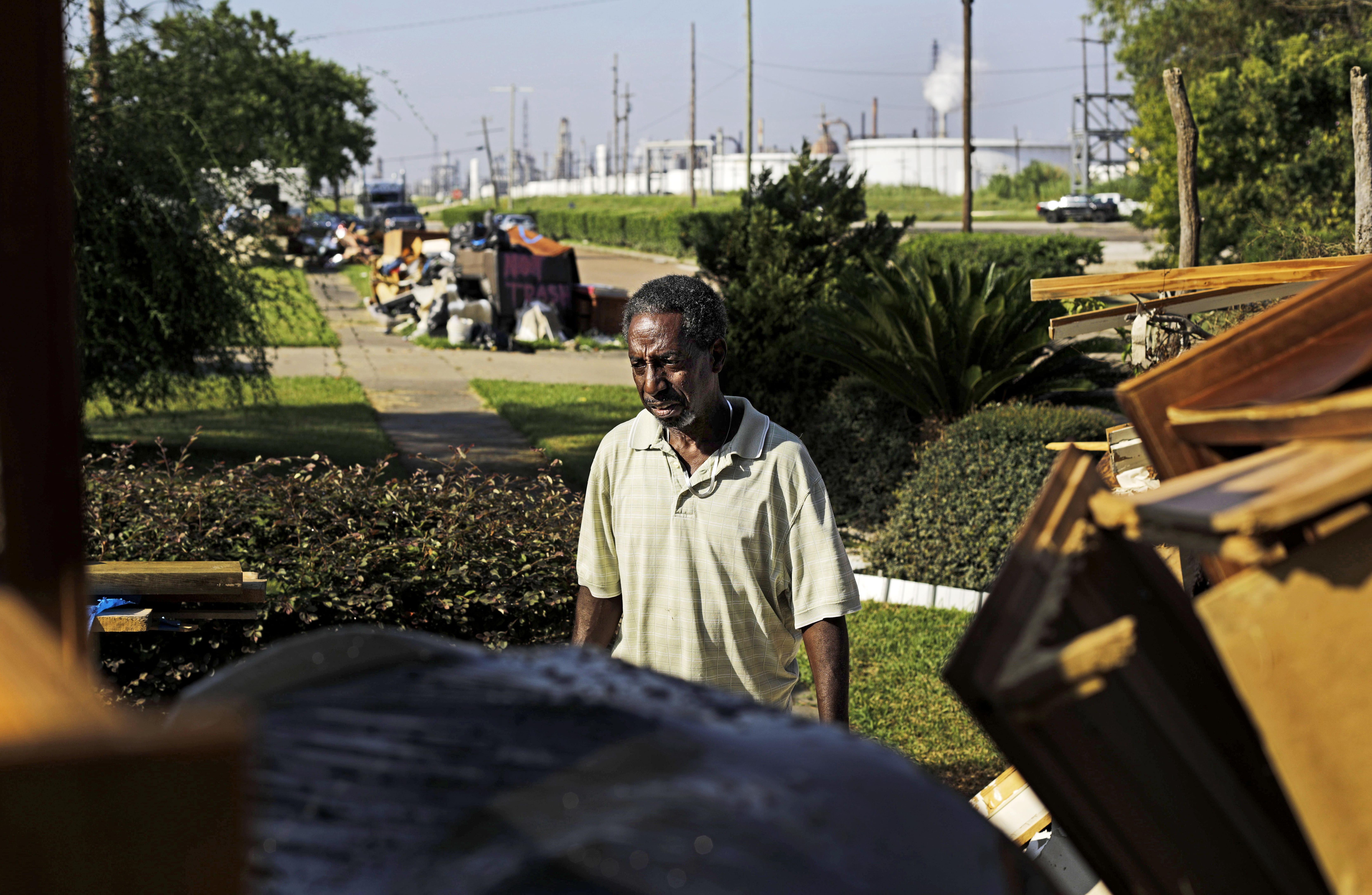 Samuel McGlory Jr. throws out debris in front of his home after Hurricane Harvey as an oil refinery stands in the background. CREDIT: AP Photo/David Goldman