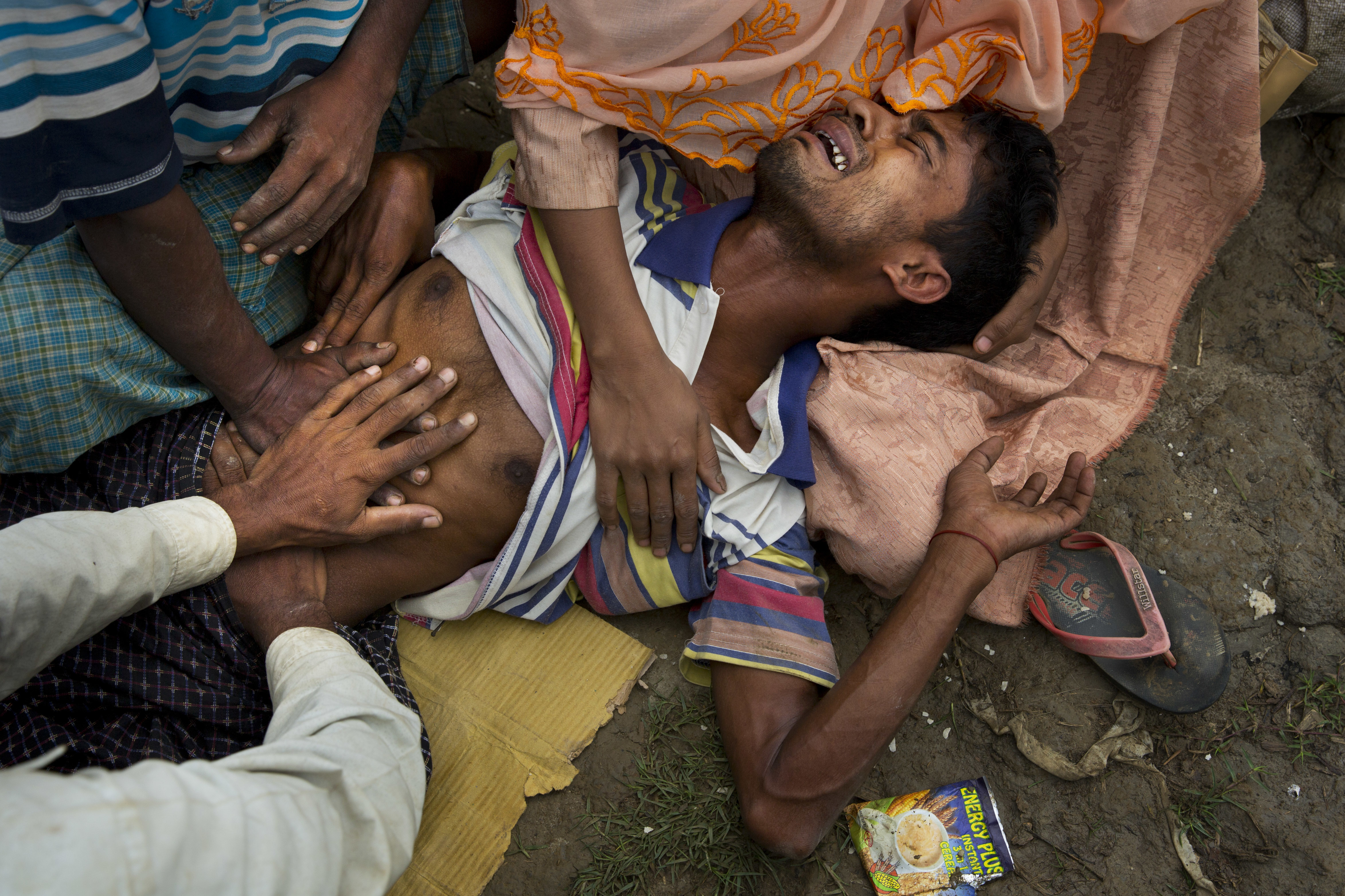 A Rohingya Muslim man, Muhammed Yunus, 28, who has not eaten for the past three days grimaces in pain as he along with others wait along the border for permission to proceed to refugee camps near Palong Khali, Bangladesh. (CREDIT: Bernat Armangue/AP Photo.