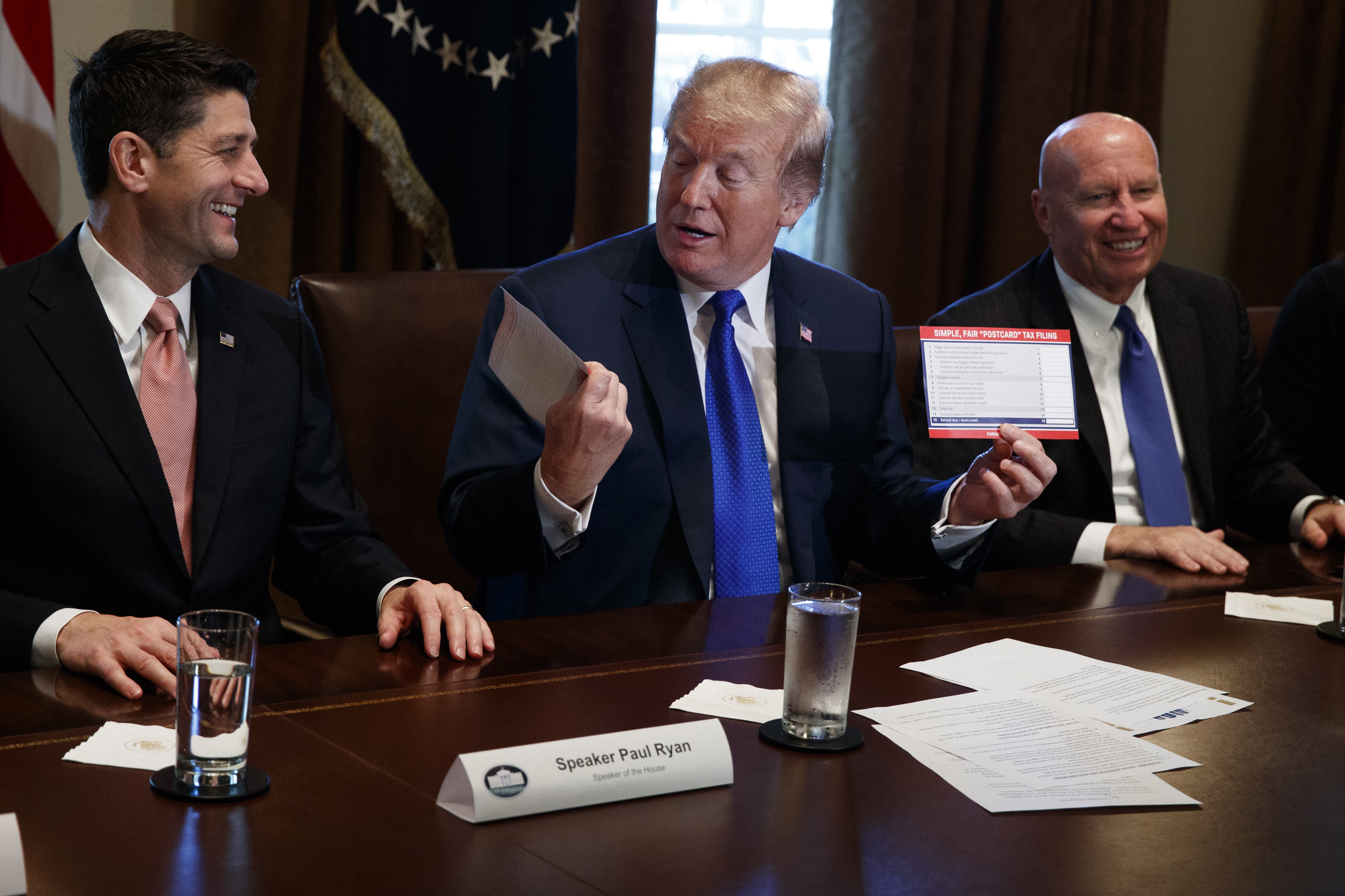 President Donald Trump holds an example of what a new tax form may look like during a meeting on tax policy with Republican lawmakers in the Cabinet Room of the White House, Thursday, Nov. 2, 2017, in Washington. From left, Speaker of the House Rep. Paul Ryan, R-Wis., Trump, and Chairman of the House Ways and Means Committee Rep. Kevin Brady, R-Texas. (AP Photo/Evan Vucci)