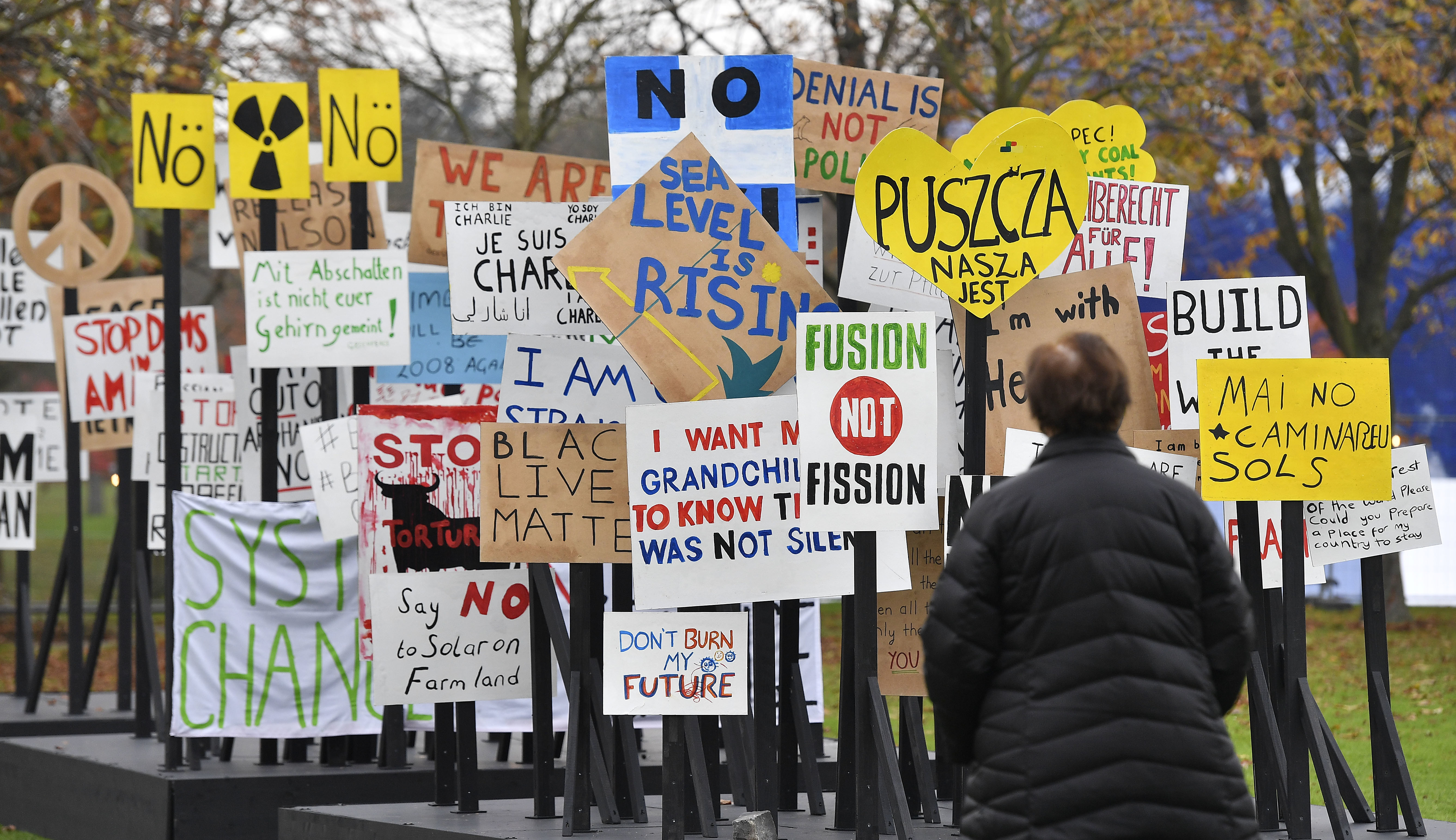 A visitor watches protest banners outside the COP 23 Fiji UN Climate Change Conference in Bonn, Germany, Monday, Nov. 6, 2017. CREDIT: AP Photo/Martin Meissner