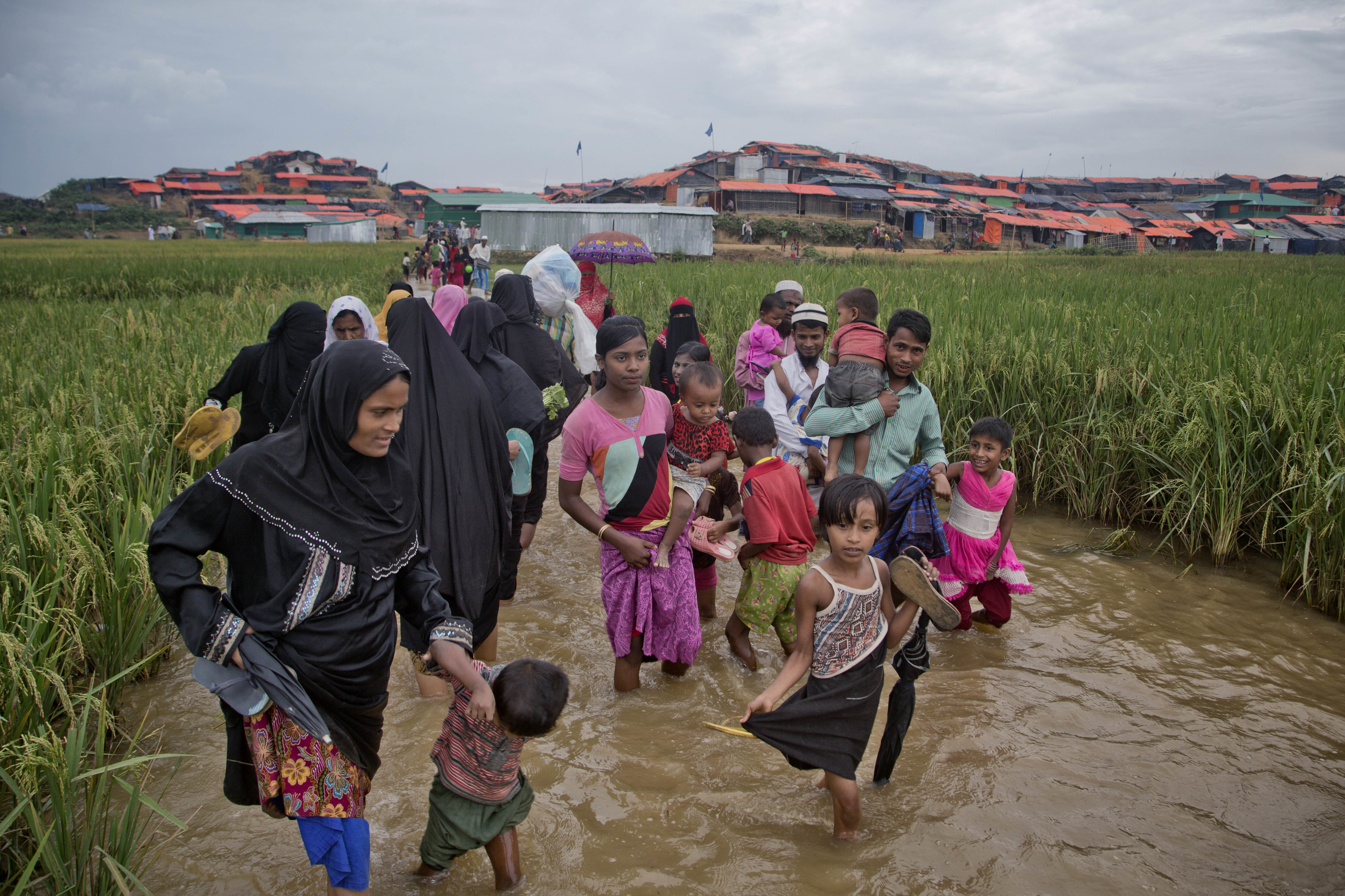Rohingya Muslims, who crossed over from Myanmar into Bangladesh, wade past a waterlogged path leading to the Jamtoli refugee camp in Ukhiya, Bangladesh, Friday, Nov. 17, 2017. CREDIT: AP Photo/A.M. Ahad