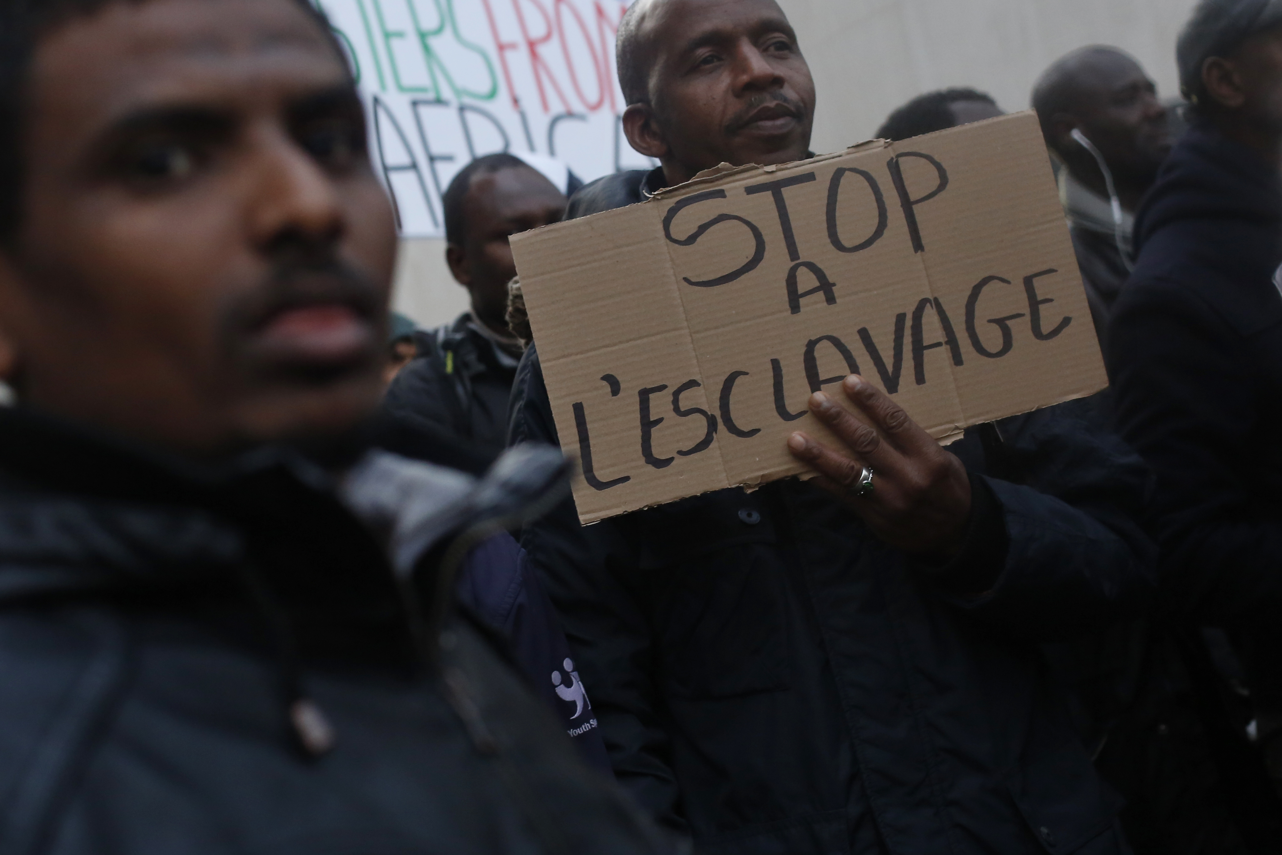 A protestor holds a placard reading "Stop slavery" as he attends a demonstration against slavery in Libya outside the Lybian Embassy in Paris, Friday, Nov. 24, 2017. Interpol says 40 suspected human traffickers have been arrested and nearly 500 of their victims freed in a vast police operation in five African countries. CREDIT: Thibault Camus/AP Photo.