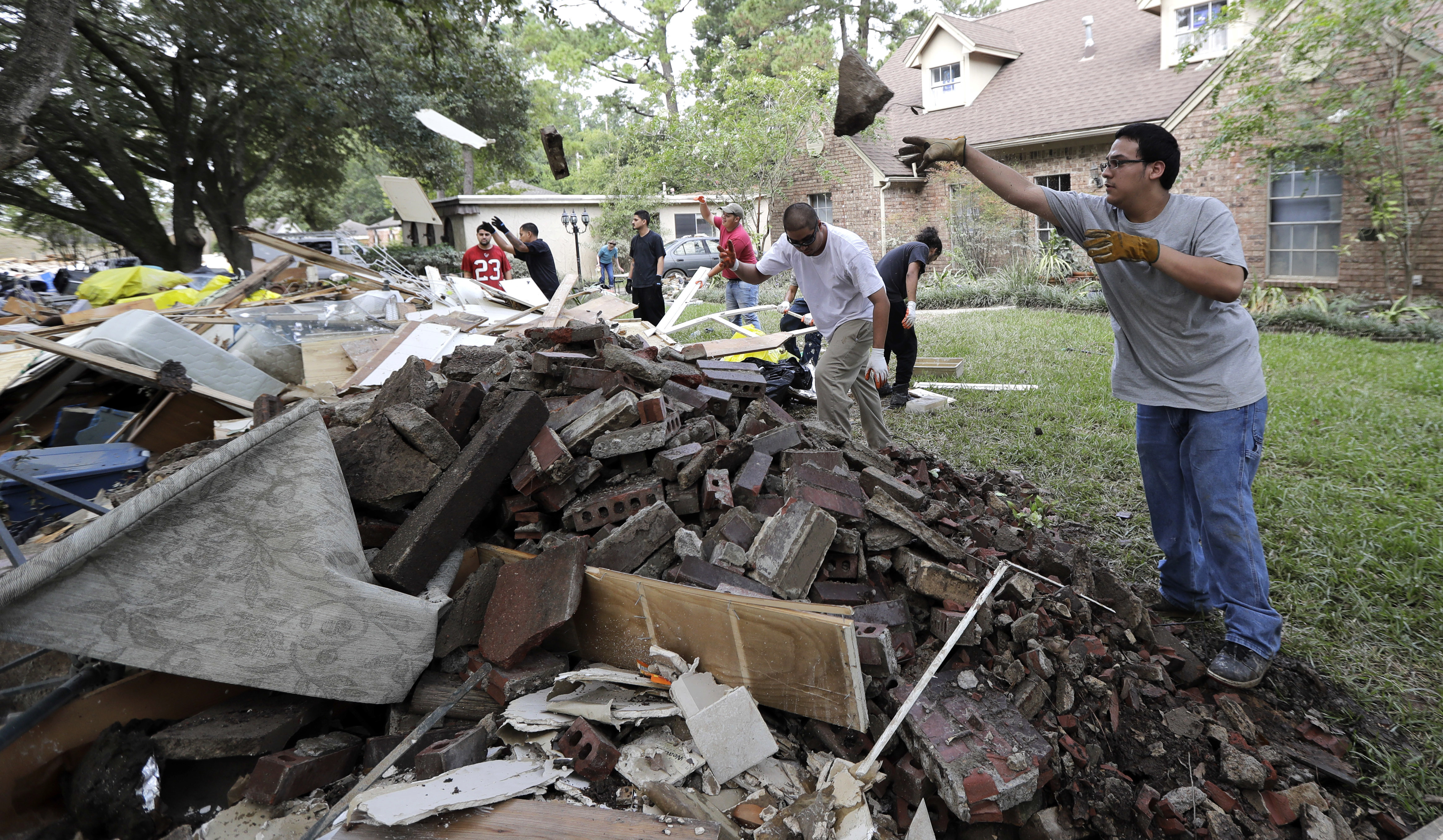 Workers help move debris from a home damaged by floodwaters in the aftermath of Hurricane Harvey on Sept. 6, 2017 in Spring, Texas. (CREDIT: AP/David J. Phillip)