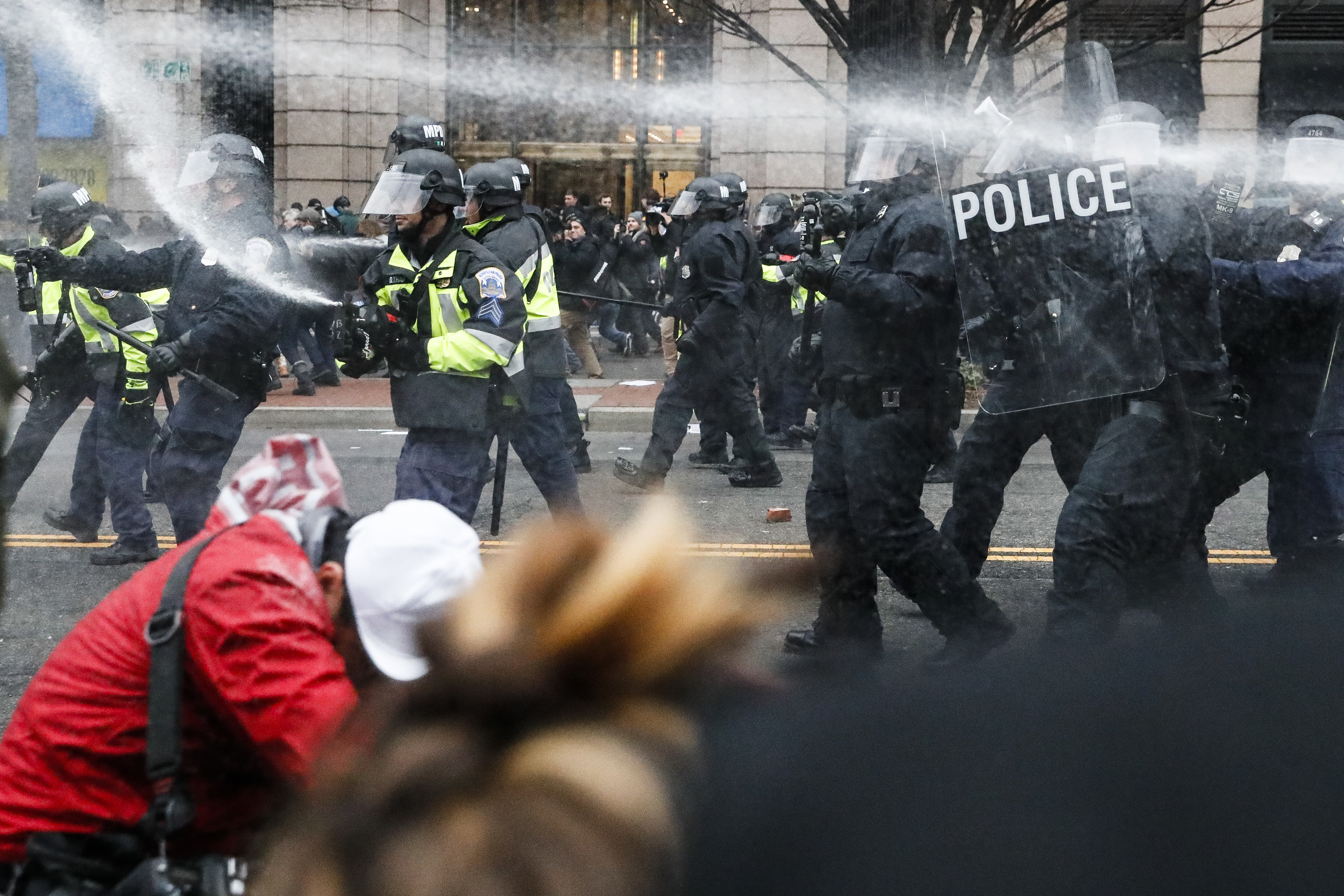 A bystander covers their face as police launch pepper spray at demonstrators on Inauguration Day 2017. CREDIT: AP Photo/John Minchillo