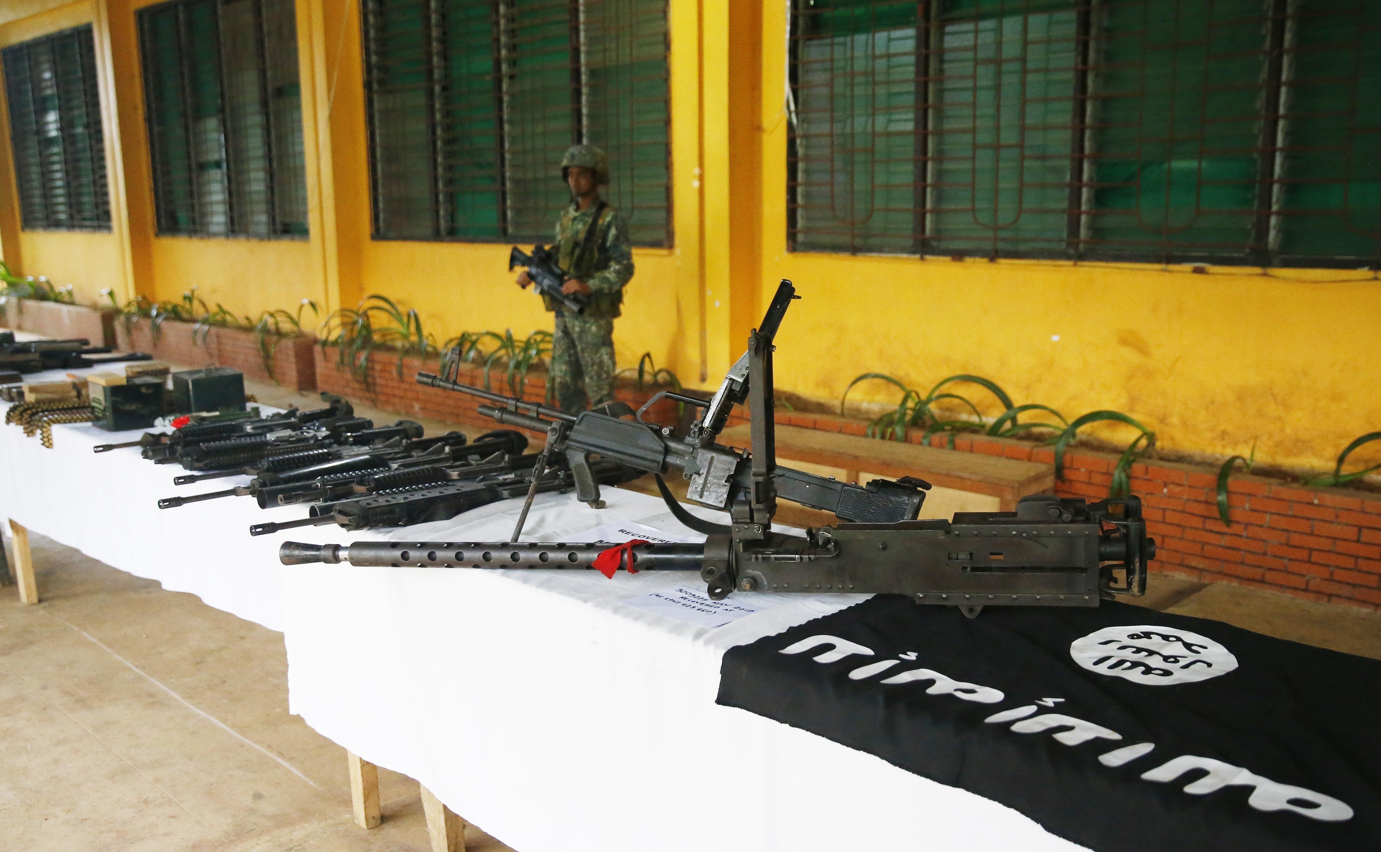 A Philippine Marine guards the display of high-powered firearms, ammunitions, uniforms and black ISIS-style flags which were recovered from Muslim militants, May 30, 2017 in Marawi city southern Philippines. (CREDIT: AP Photo/Bullit Marquez)