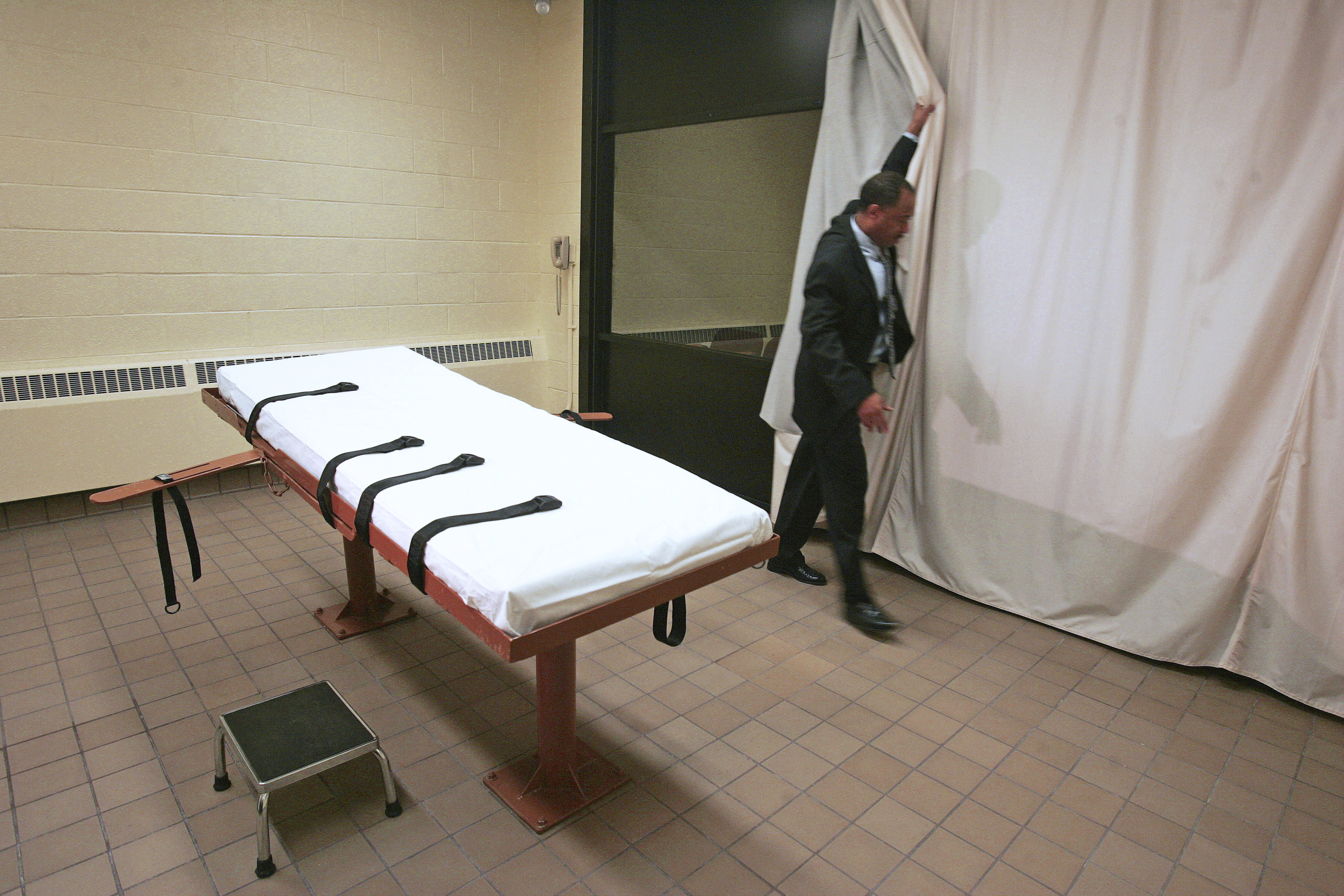 In this Nov. 2005 file photo, Larry Greene, public information director of the Southern Ohio Correctional Facility, demonstrates how a curtain is pulled between the death chamber and witness room at the prison in Lucasville, Ohio. CREDIT: AP Photo/Kiichiro Sato, File