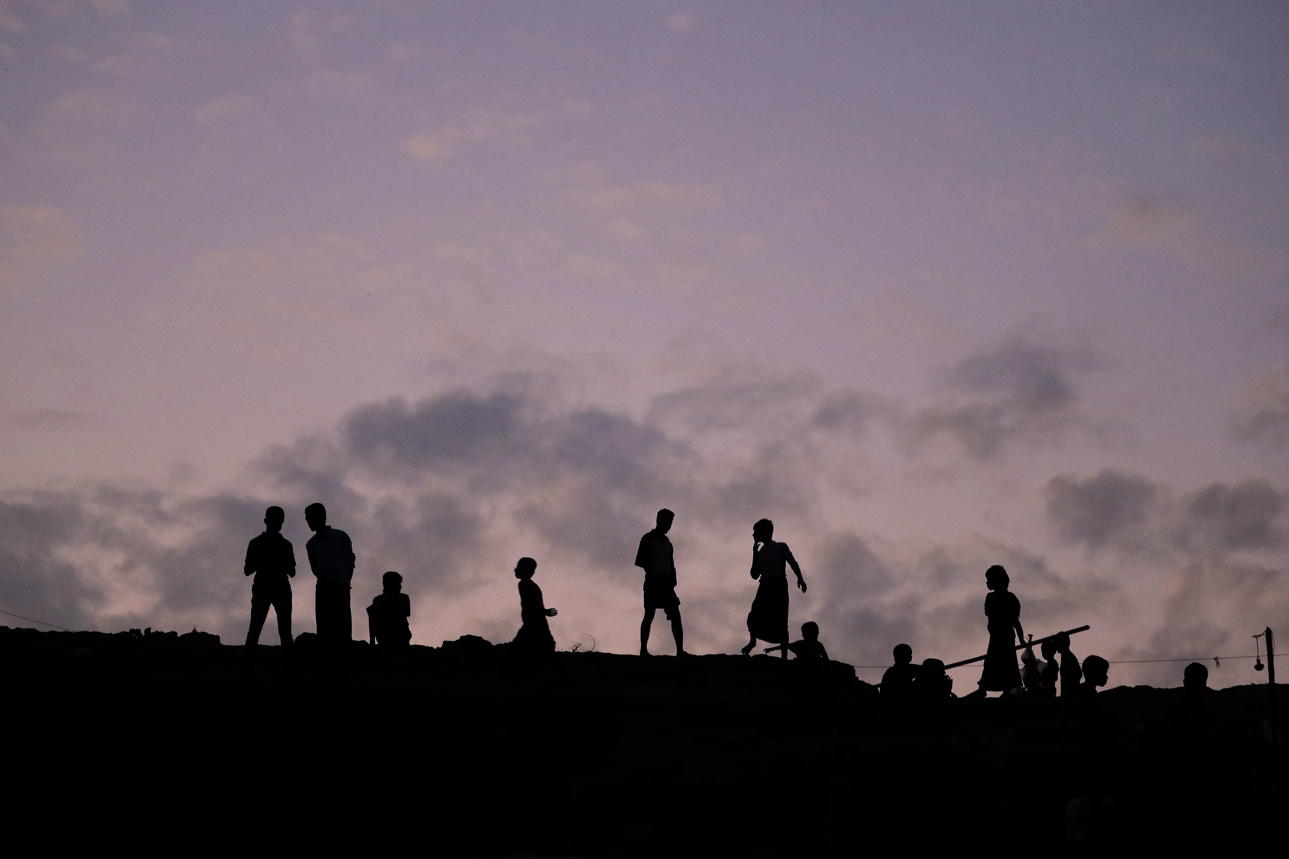 Rohingya Muslims are silhouetted against the dusk sky in Jamtoli refugee camp on Friday, Nov. 24, 2017, in Bangladesh. Since late August, more than 620,000 Rohingya have fled Myanmar's Rakhine state into neighboring Bangladesh, seeking safety from what the military described as "clearance operations." The United Nations and others have said the military's actions appeared to be a campaign of "ethnic cleansing," using acts of violence and intimidation and burning down homes to force the Rohingya to leave their communities. (AP Photo/Wong Maye-E)