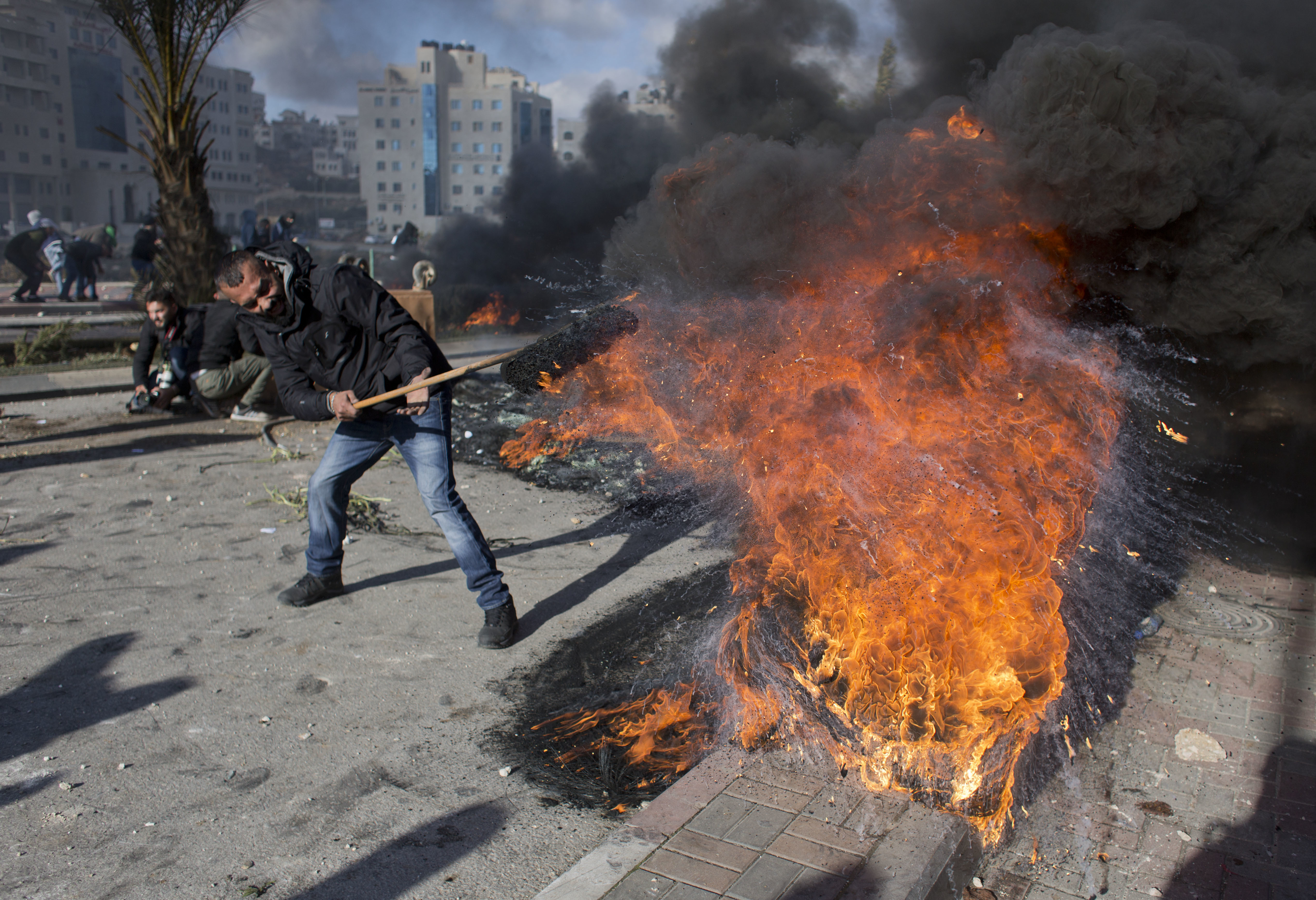 A Palestinian protester burns tires during clashes with Israeli troops following protests against President Donald Trump's decision to recognize Jerusalem as the capital of Israel, in the West Bank city of Ramallah, Thursday, Dec. 7, 2017. CREDIT: Nasser Nasser/AP Photo.