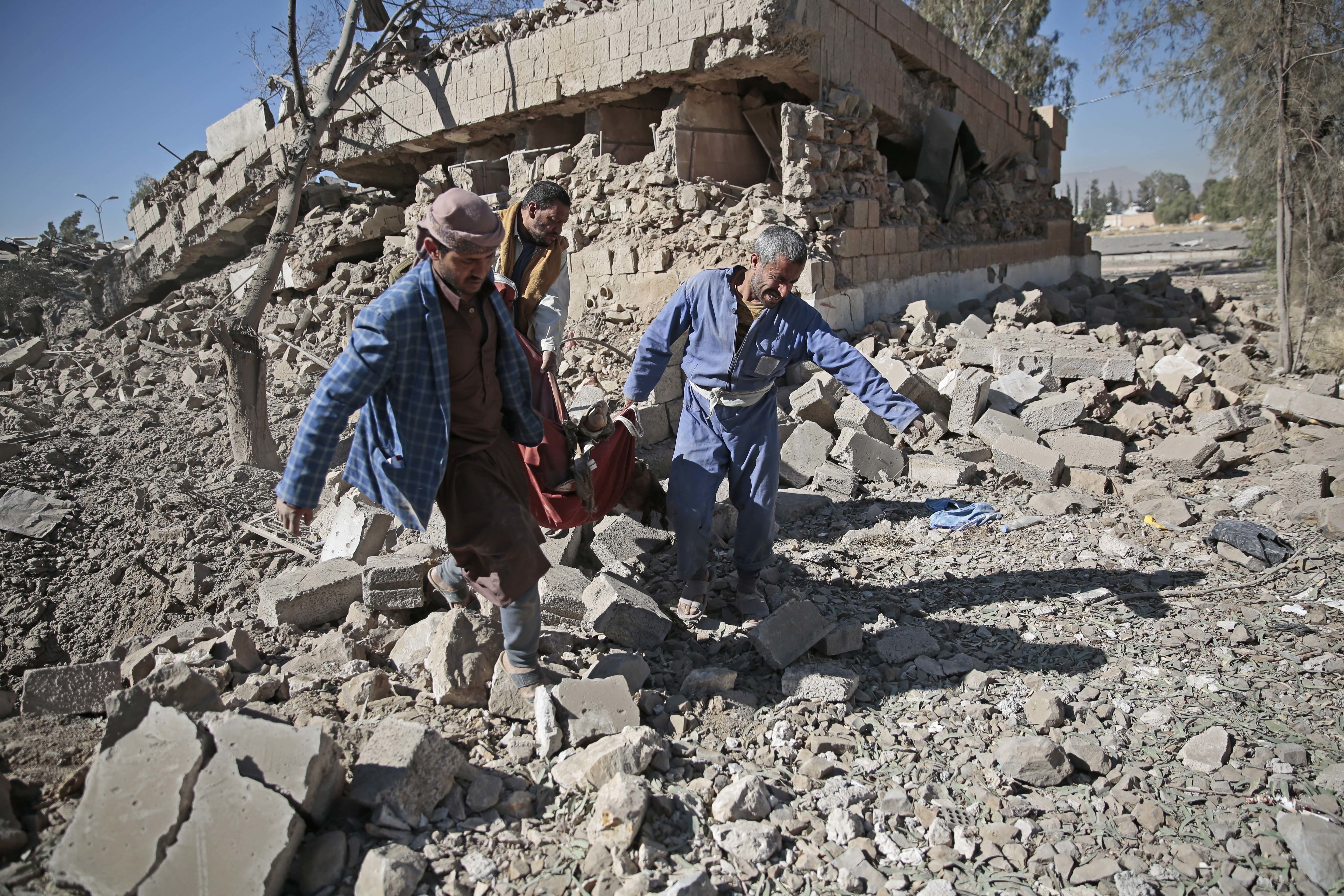 People carry the body of a man they uncovered from under the rubble of a Houthi-held detention center destroyed by Saudi-led airstrikes in Sanaa, Yemen, Wednesday, Dec. 13, 2017. CREDIT: Hani Mohammed/AP Photo.