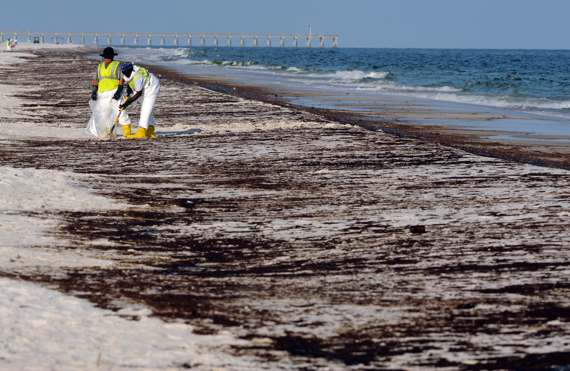 Crews work to clean up oil from the Deepwater Horizon oil spill washed ashore at Pensacola Beach in Pensacola, Florida. CREDIT: AP Photo/ Michael Spooneybarger
