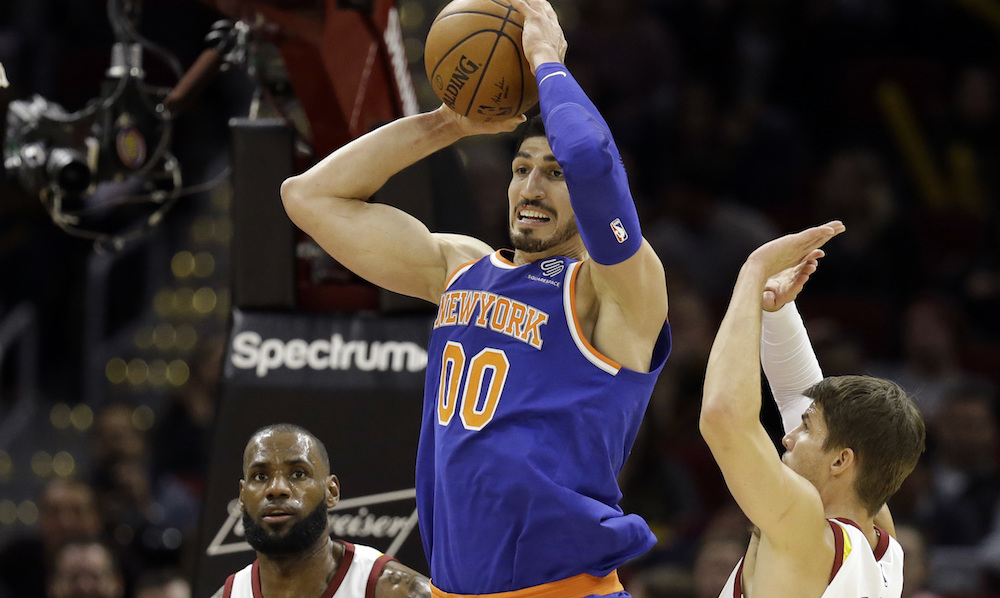 New York Knicks' Enes Kanter (00) passes between Cleveland Cavaliers' LeBron James (23) and Kyle Korver (26) in the first half of an NBA basketball game, Sunday, Oct. 29, 2017, in Cleveland. (AP Photo/Tony Dejak)