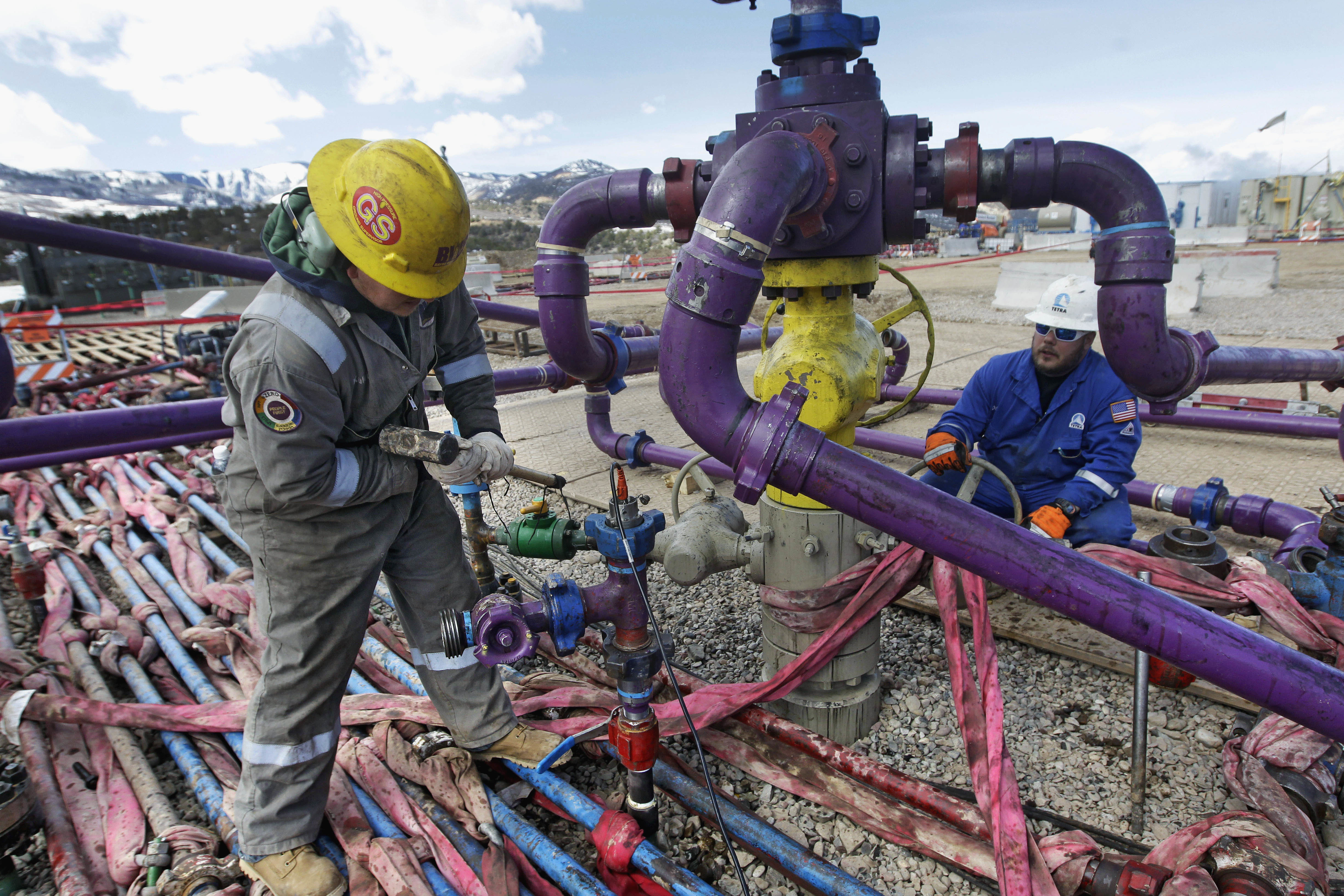 Workers tend to a well head during a hydraulic fracturing operation in western Colorado. (CREDIT: AP Photo/Brennan Linsley, File)