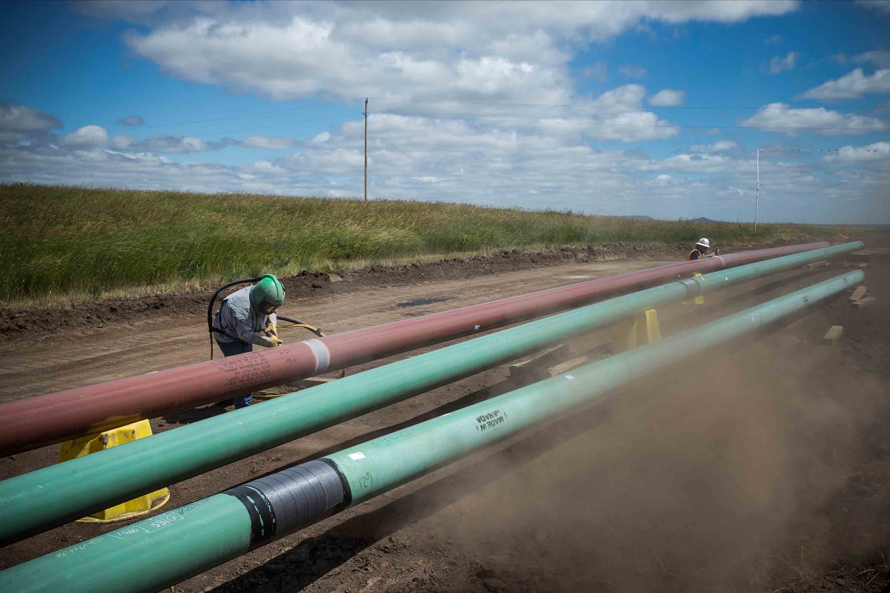 A construction worker specializing in pipe-laying sandblasts a section of pipeline on July 25, 2013 outside Watford City, North Dakota. (CREDIT: Andrew Burton/Getty Images)
