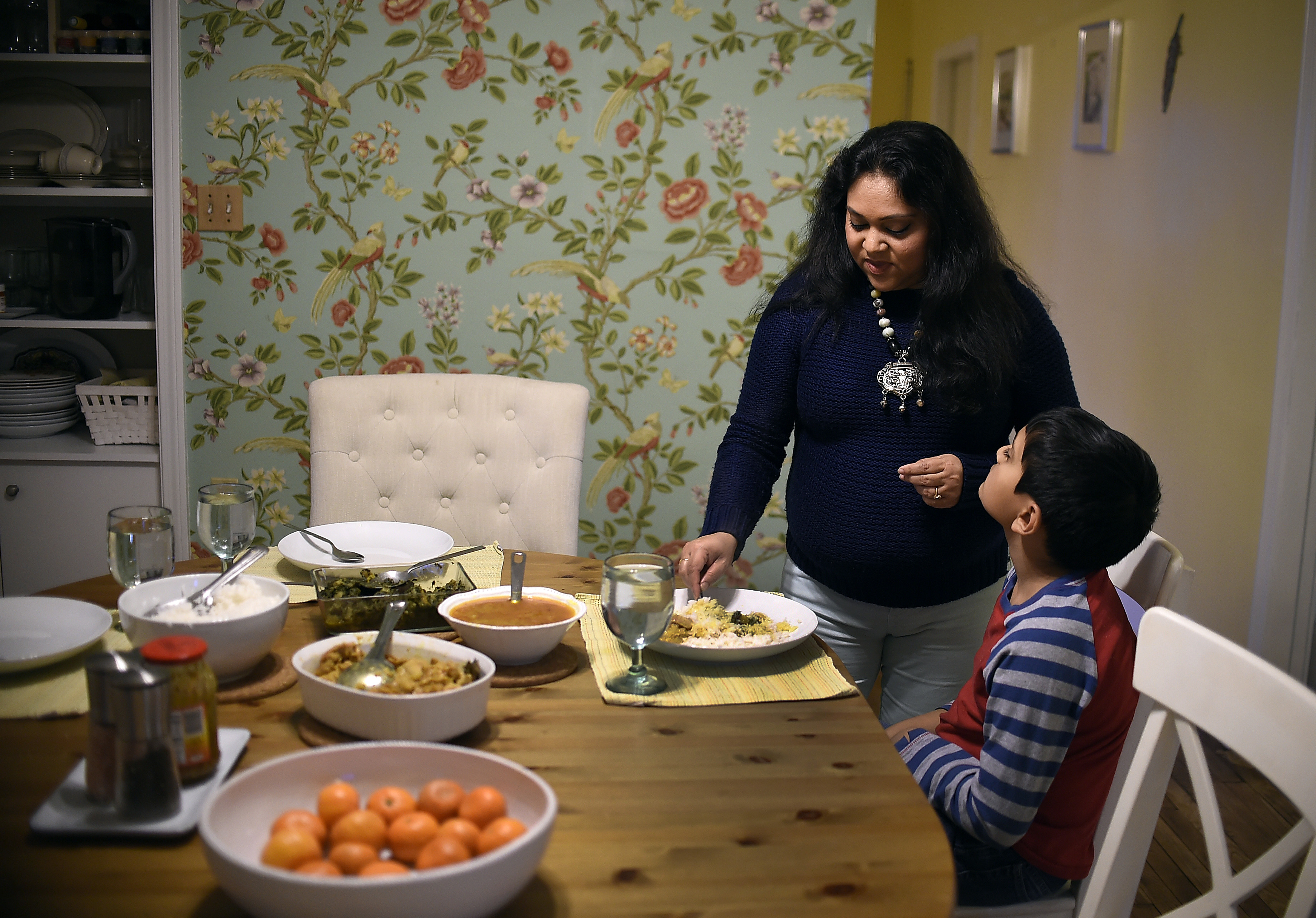Sudarshana Sengupta, left, fixes a dinner plate for her son, Josh. Sengupta, a research associate and legal immigrant from India, has been waiting for her green card since being approved in 2010. (CREDIT: Jessica Hill/For The Washington Post via Getty Images)