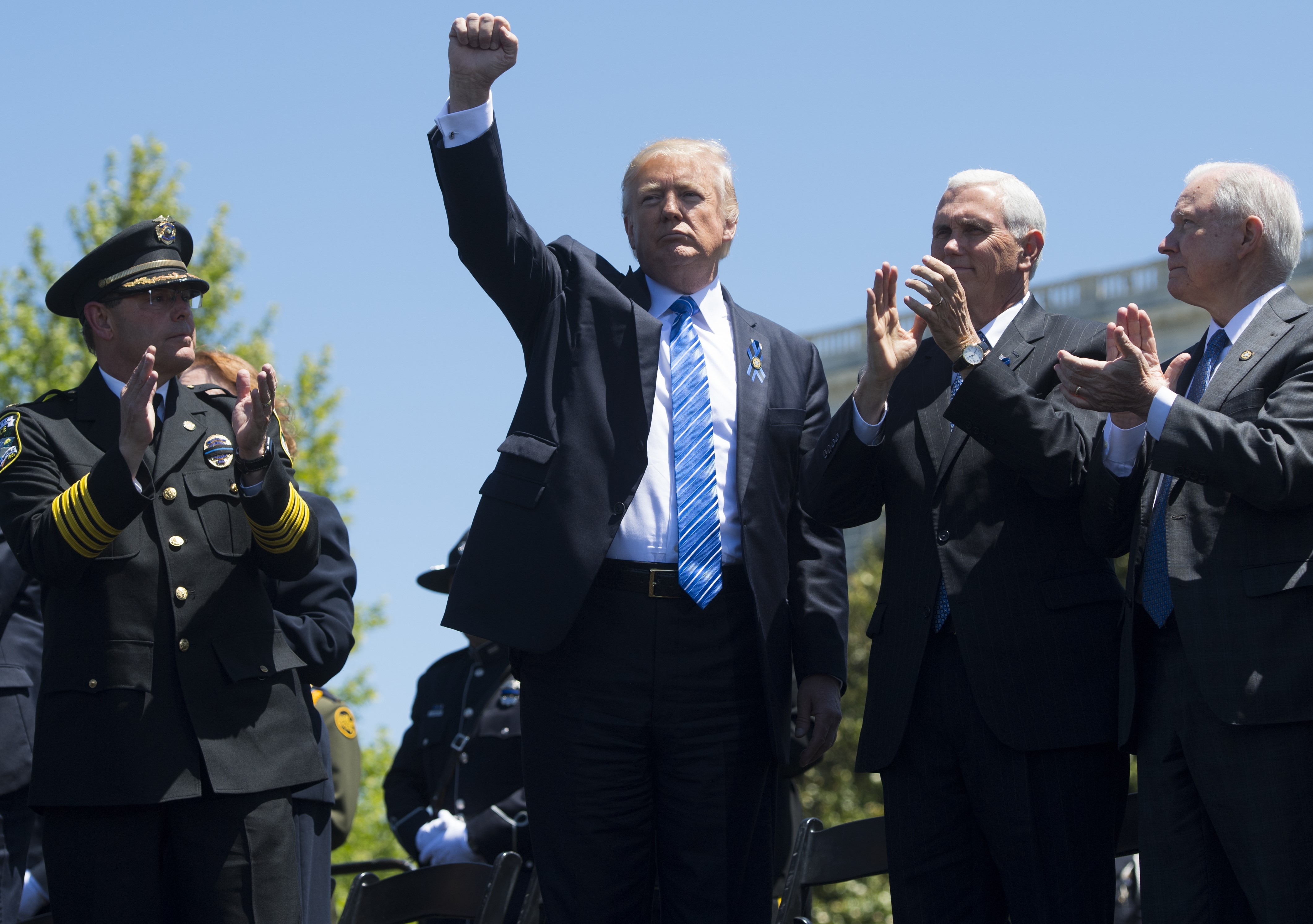 President Donald Trump waves after speaking alongside US Vice President Mike Pence (2nd R) and Attorney General Jeff Sessions (R) during the 36th Annual National Peace Officers Memorial Service at the US Capitol in Washington, DC. CREDIT: Saul Loeb/AFP Photo/Getty Images.