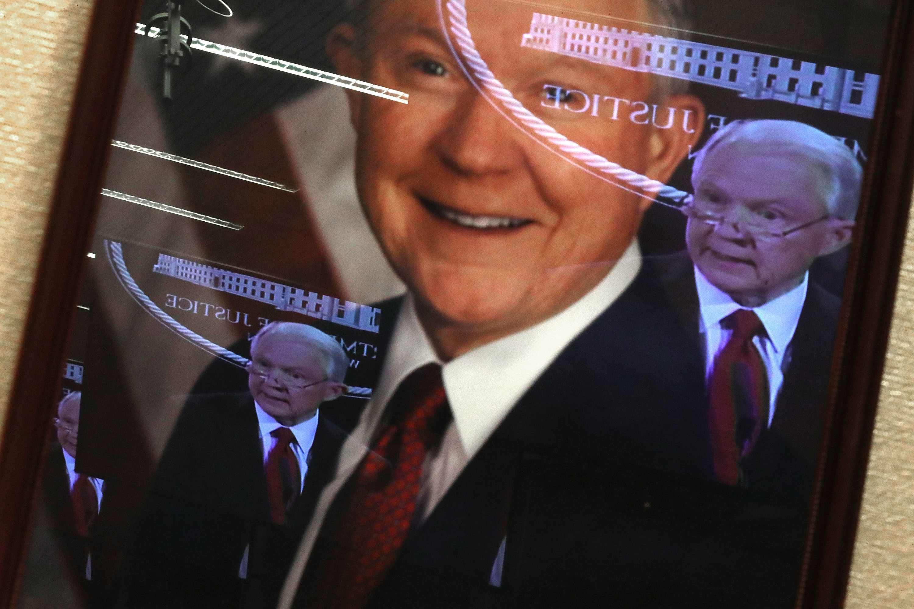 U.S. Attorney General Jeff Sessions' television image is reflected in his official portrait during a news conference at the Department of Justice on December 15, 2017 in Washington, DC. CREDIT: Photo by Chip Somodevilla/Getty Images