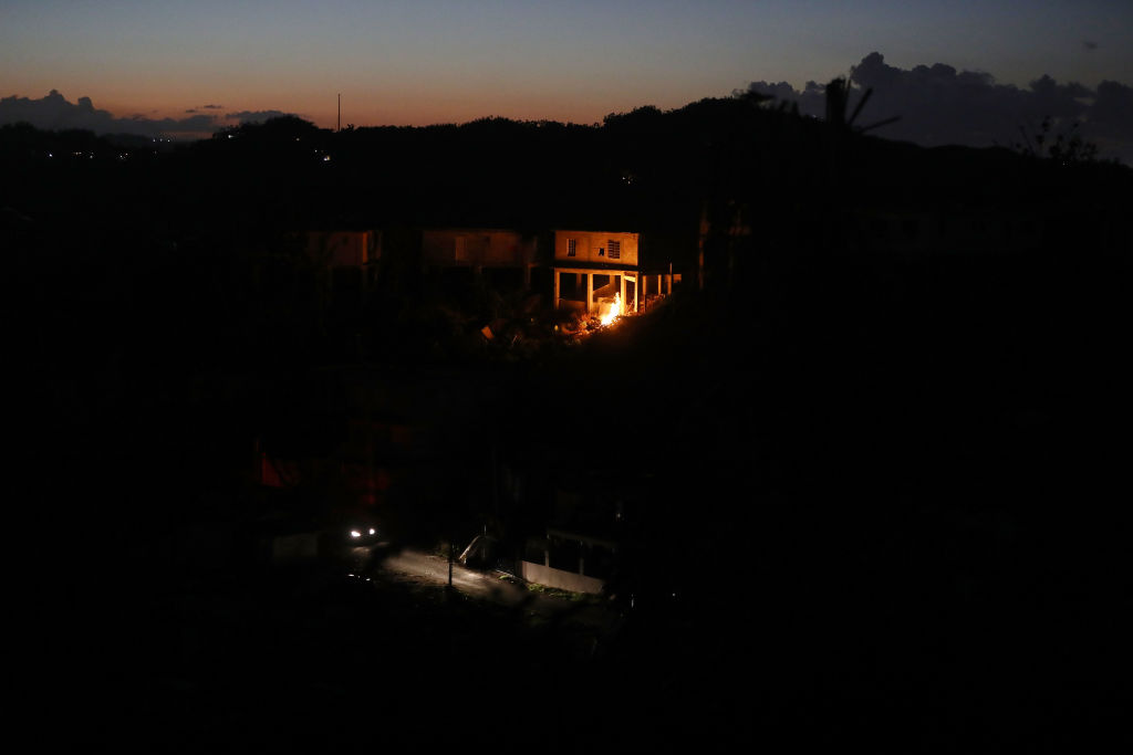 Just before Christmas, a trash fire illuminates houses in a Puerto Rican neighborhood without power as a car passes. CREDIT: Mario Tama/Getty Images