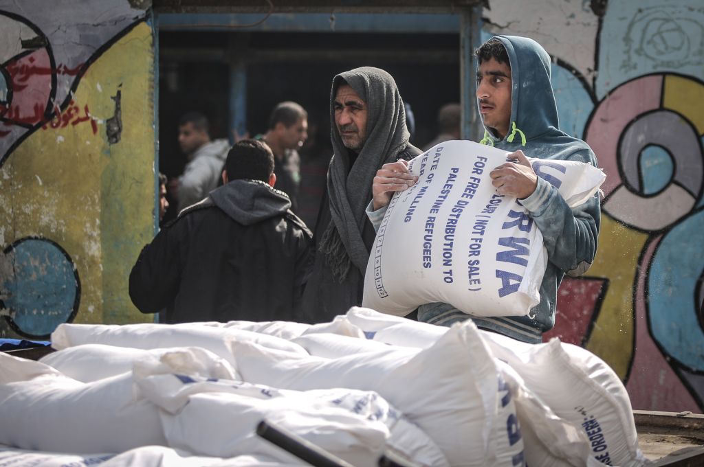 A man carries sacks of flours during a food aid distribution by the United Nations Relief and Works Agency for Palestine Refugees in the Near East (UNRWA) at Al-Shati Refugee Camp in Gaza City, Gaza on January 15, 2018. CREDIT: Photo by Ali Jadallah/Anadolu Agency/Getty Images