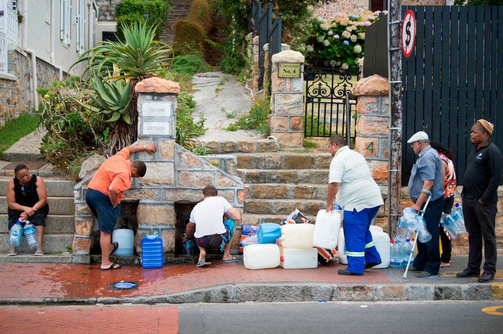 People collect drinking water from pipes fed by an underground spring, on January 19, 2018, in Cape Town. (CREDIT: RODGER BOSCH/AFP/Getty Images)