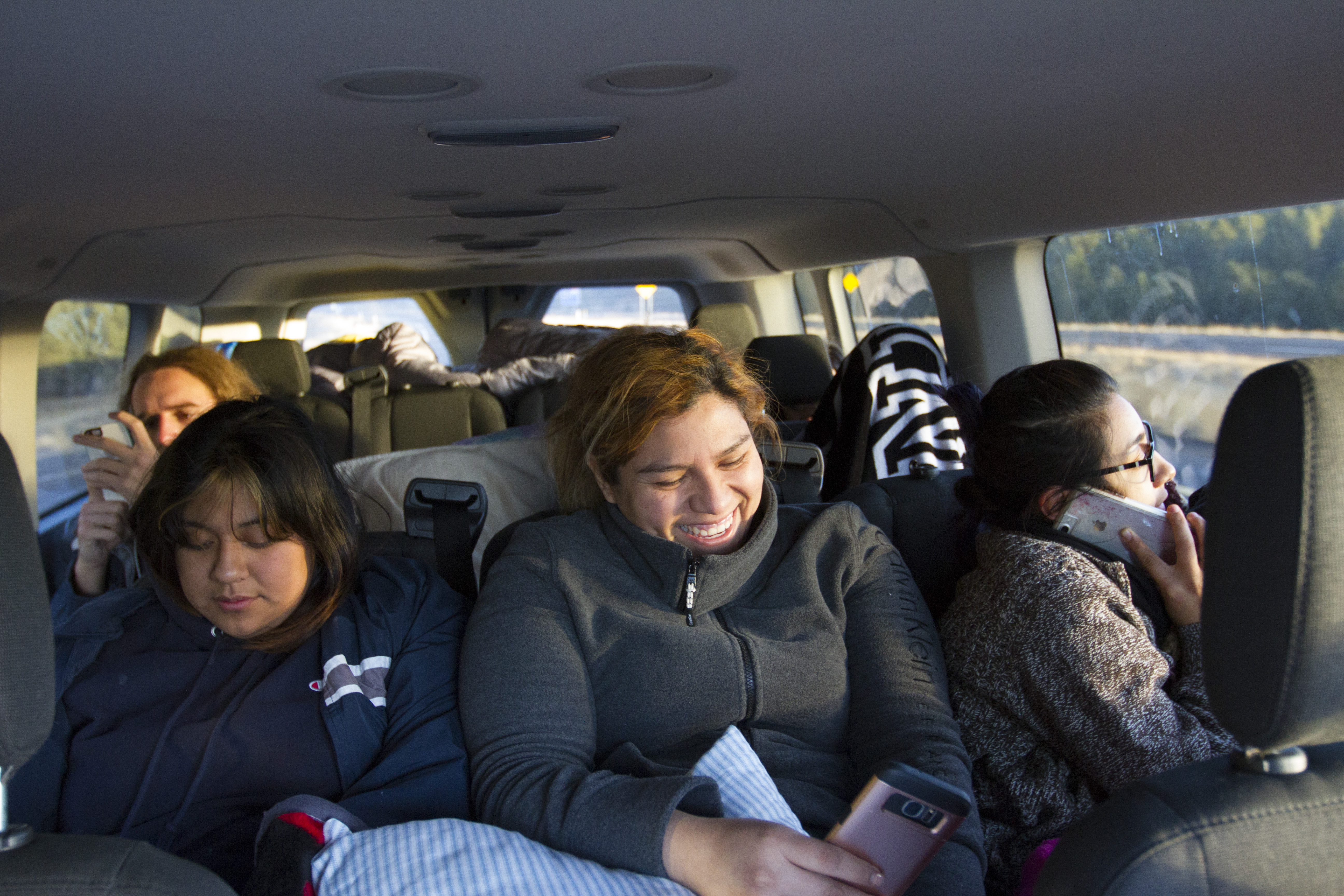Susana Nava, 30, laughs at her phone as the group of DACA recipients and advocates enter Arizona on 40 hour drive back from Washington D.C. on Dec. 10, 2017. (Credit: Megan Janetsky)