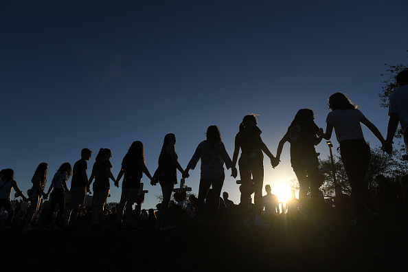 Students and their family members join hands outside Marjory Stoneman Douglas High School on Sunday February 18, 2018 in Parkland, FL. A shooting on Wednesday at the school left 17 people dead. (Photo by Matt McClain/The Washington Post via Getty Images)