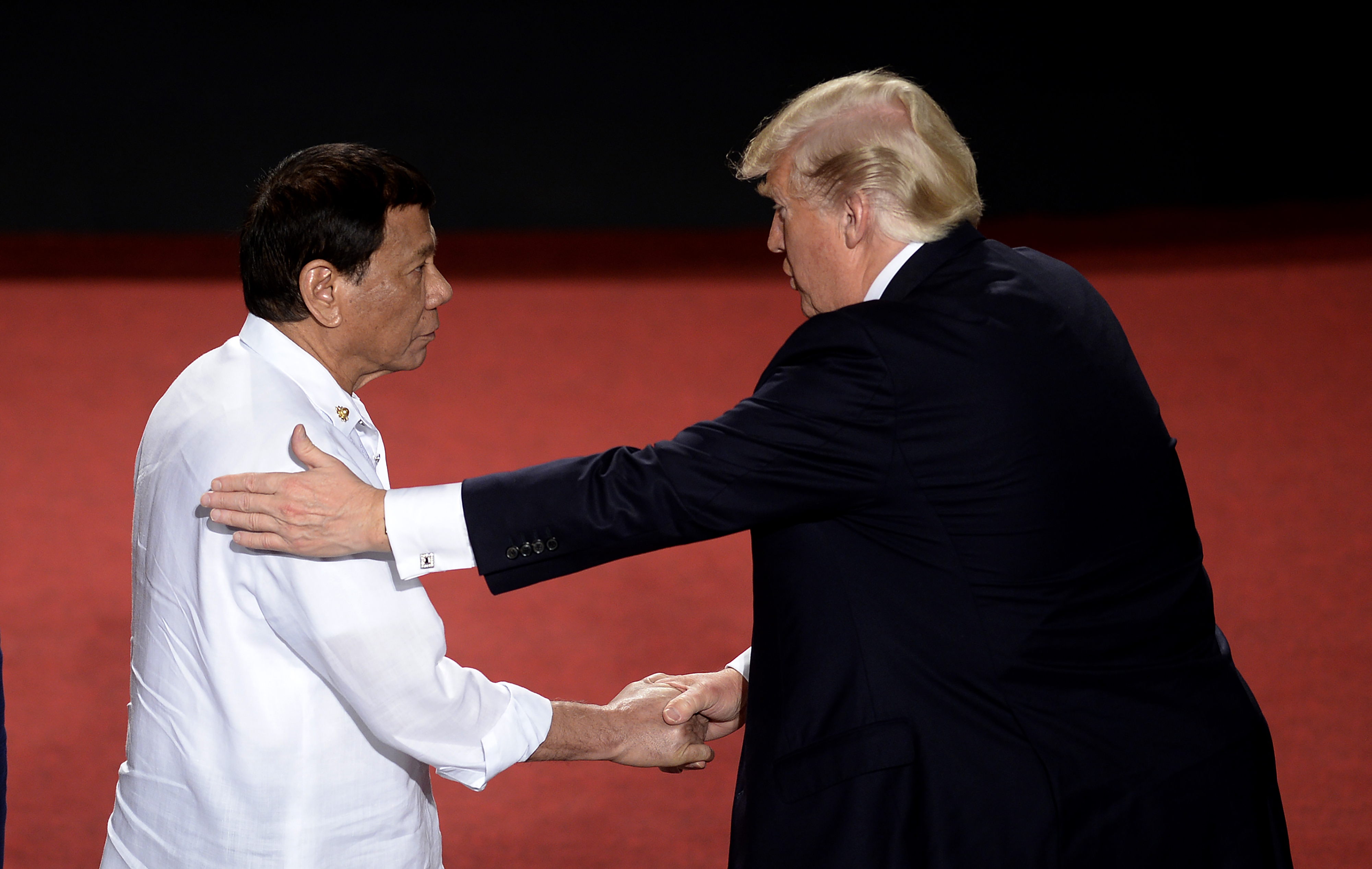Philippine President Rodrigo Duterte, whose soldiers and police have killed thousands in a bloody drug crackdown, shakes hands with U.S. President Donald Trump (R) in 2017. CREDIT: NOEL CELIS/AFP/Getty Images