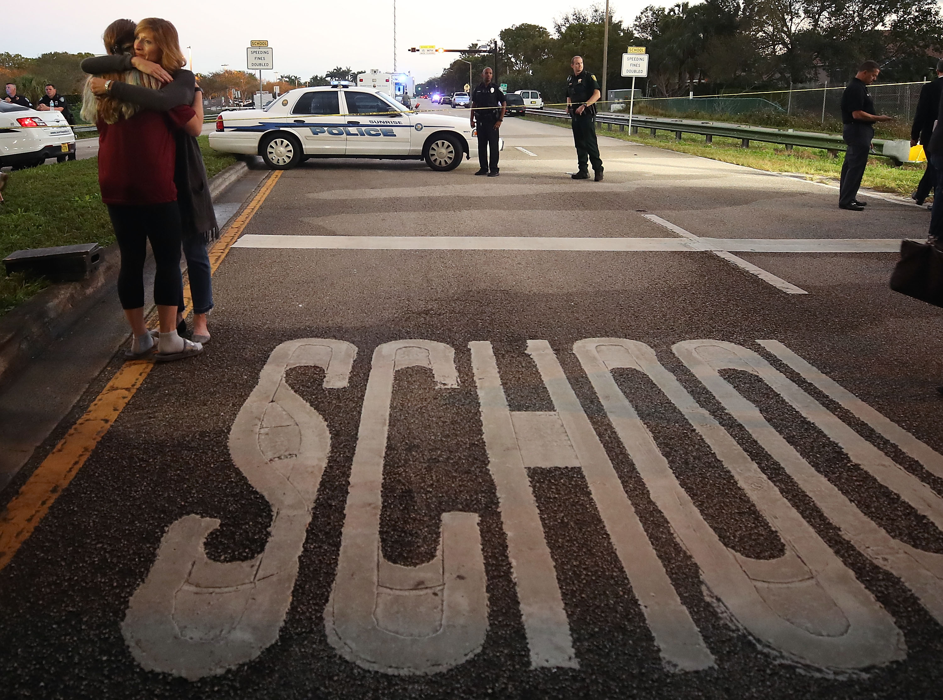 Kristi Gilroy (R), hugs a young woman at a police check point near the Marjory Stoneman Douglas High School where 17 people were killed by a gunman yesterday, on February 15, 2018 in Parkland, Florida. CREDIT: Photo by Mark Wilson/Getty Images