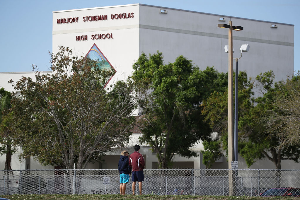 Charles Lambeth and Joey Wong (l-r) alumni of the Marjory Stoneman Douglas High School look on at the school on February 18, 2018 in Parkland, Florida. (CREDIT: Joe Raedle/Getty Images)