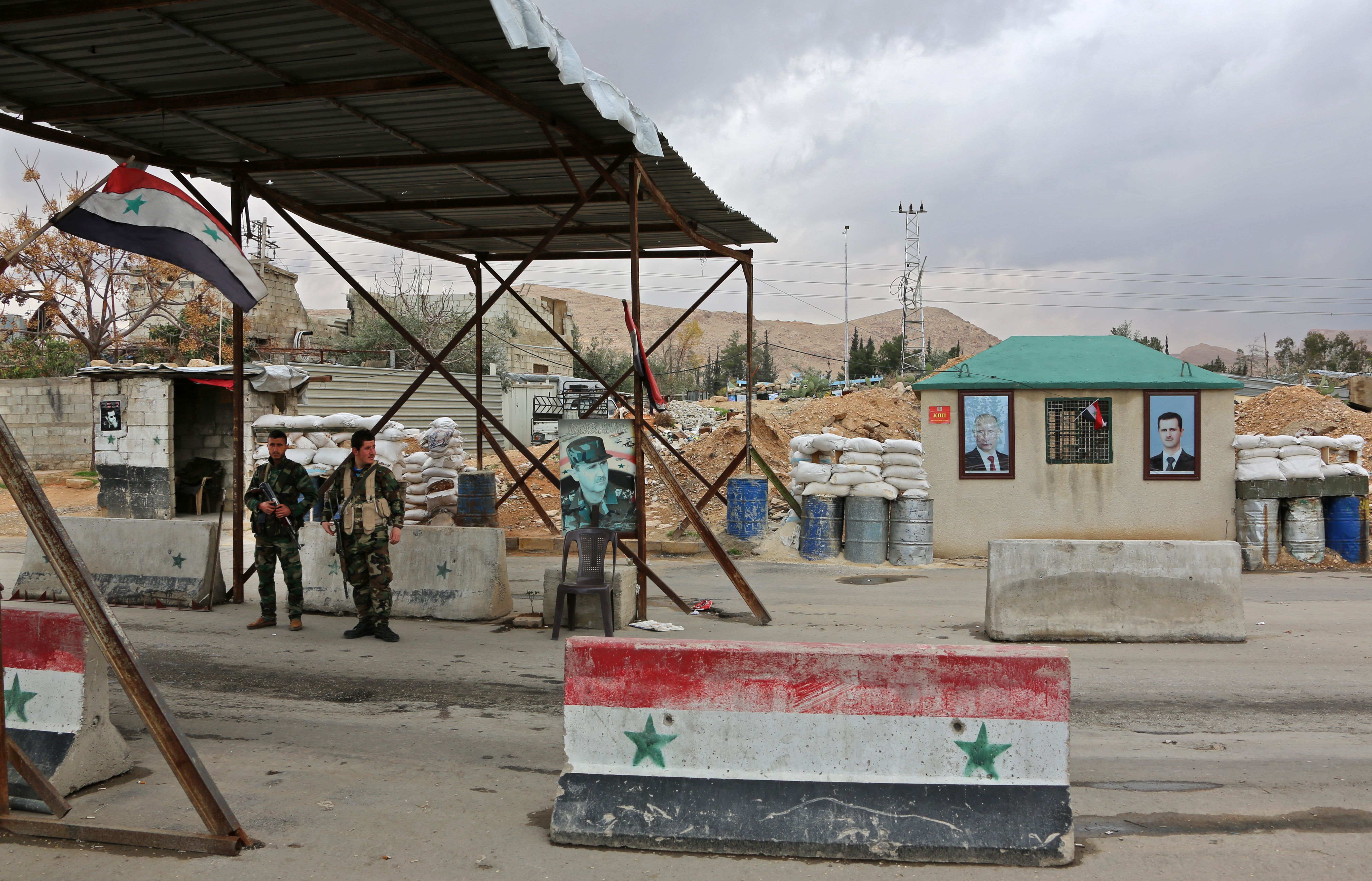 Members of the Syrian government forces stand at the Wafideen checkpoint on the outskirts of Damascus neighbouring the rebel-held Eastern Ghouta region on February 27, 2018 during an operation that would allow some of the nearly 400,000 people living in the rebel-held area to leave the battered enclave through safe corridors. (CREDIT: Stringer/AFP/Getty Images)