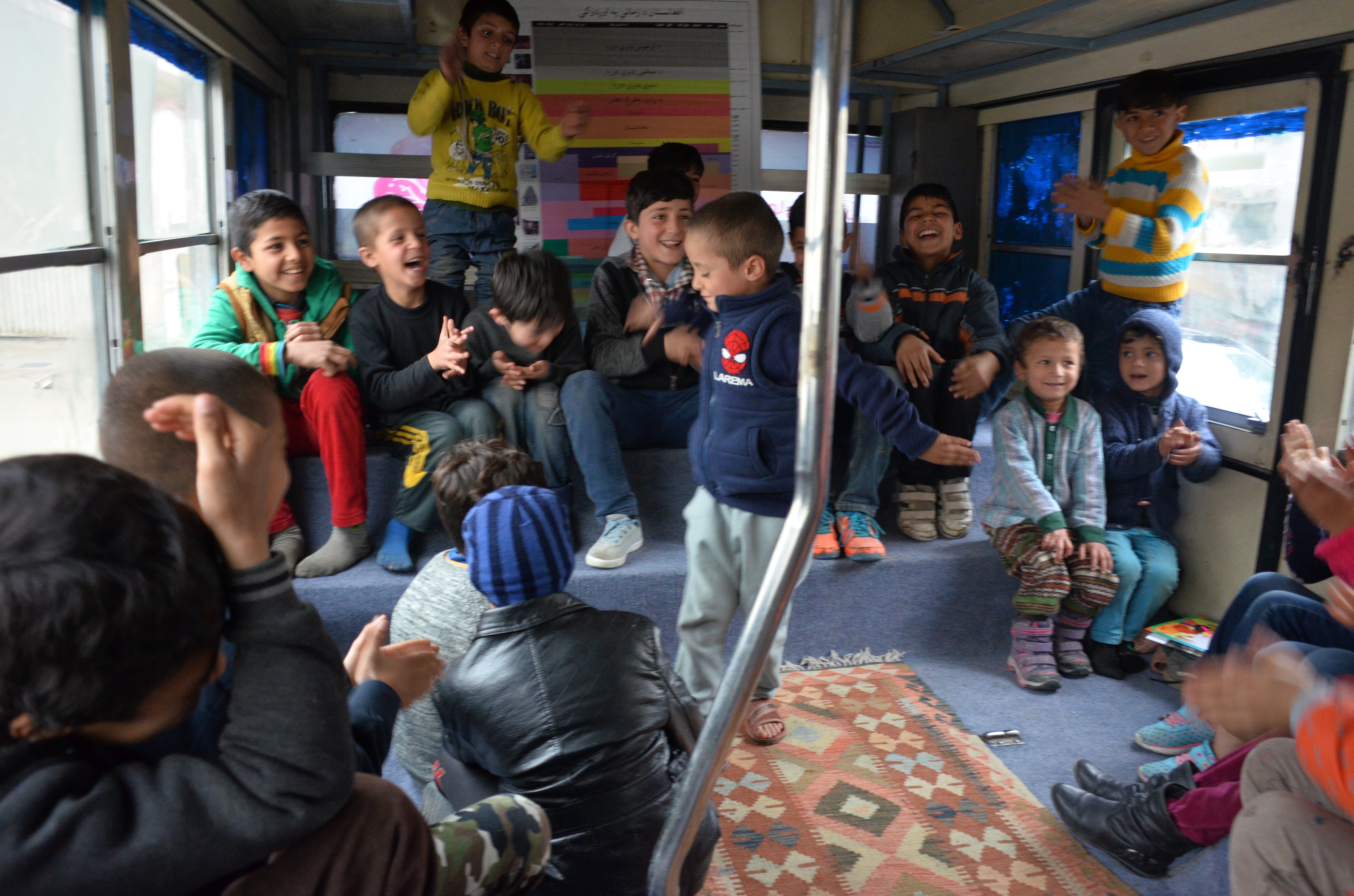 The youth of Charmaghz mobile library laugh and clap together. (credit: Ali M. Latifi for ThinkProgress)