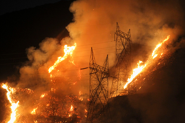 Flames flare up next to electric poles from the Blue Cut wildfire near Cajon Pass, north of San Bernardino, California on August 16, 2016. CREDIT: RINGO CHIU/AFP/Getty Images