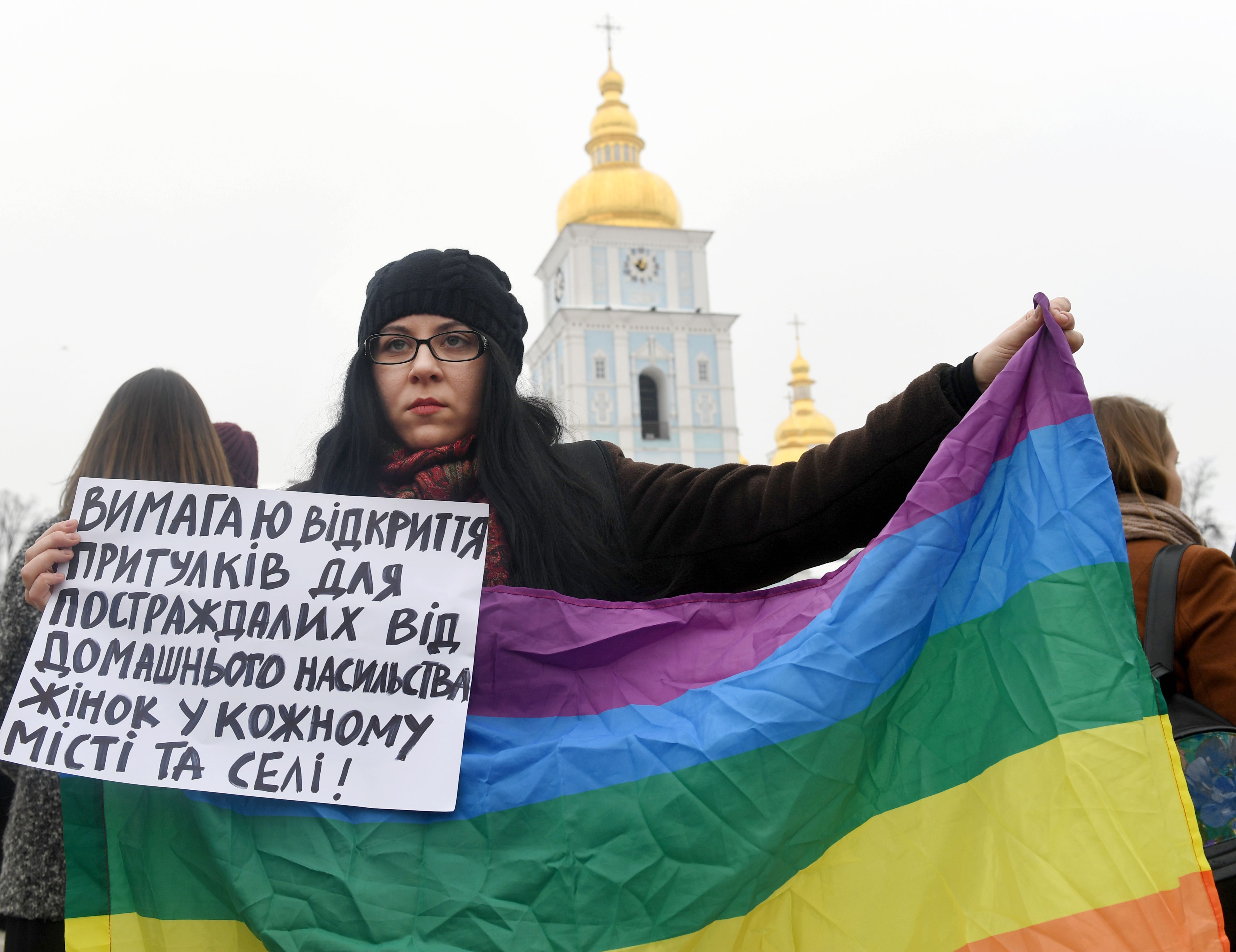 Activist holds LGBT flag and placard reading, "I demand the opening of shelters for victims of domestic violence in every city" during a march by feminists in the Ukrainian capital of Kiev, a they mark International Women's Day on March 8, 2018.
Participants of the march urged the Ukrainian authorities to ratify the Istanbul Convention of the Council of Europe on the prevention of violence against women and domestic violence. (CREDIT: SERGEI SUPINSKY/AFP/Getty Images)