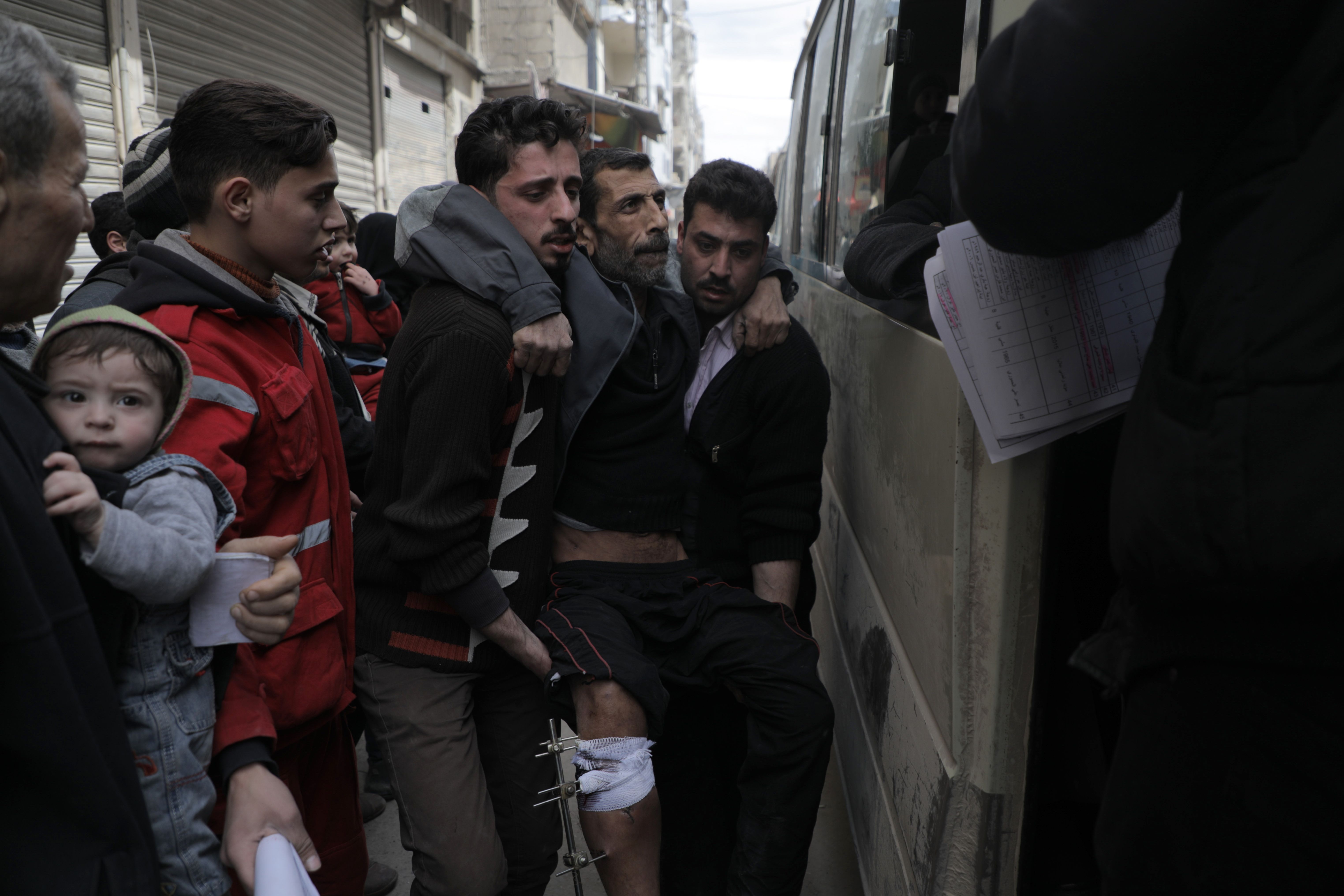 Syrian men help another boarding Syrian Red Crescent buses evacuating humanitarian cases from Douma in the rebel-held enclave of Eastern Ghouta to the government-controlled Wafidin crossing on the eastern outskirts of the capital Damascus on March 18, 2018. CREDIT: Hamza al-Ajweh/AFP/Getty Images.