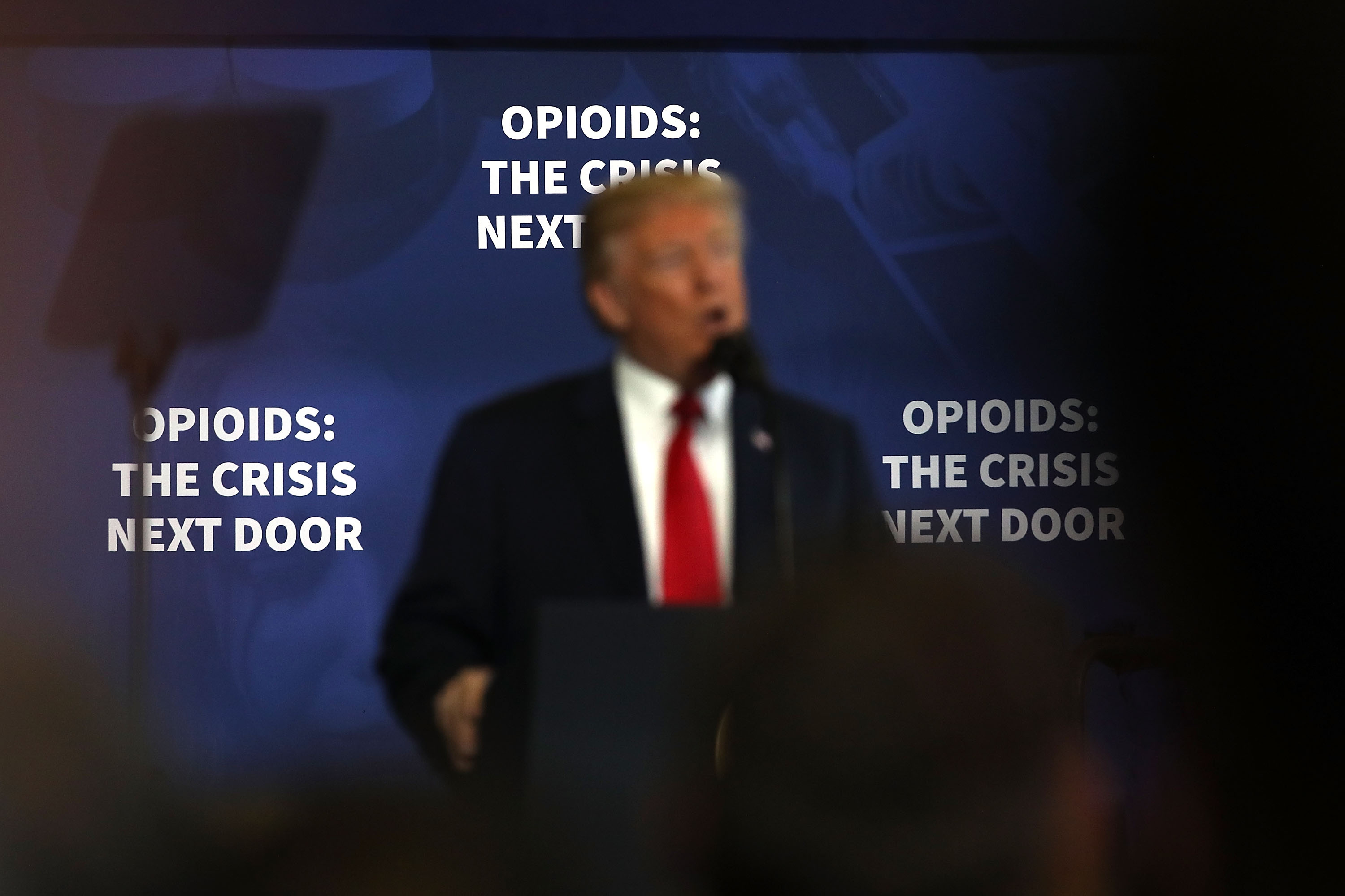 President Donald Trump, out of focus, gives rambling remarks ostensibly meant to unveil specific new policies for addressing drug addiction. CREDIT: Spencer Platt/Getty Images