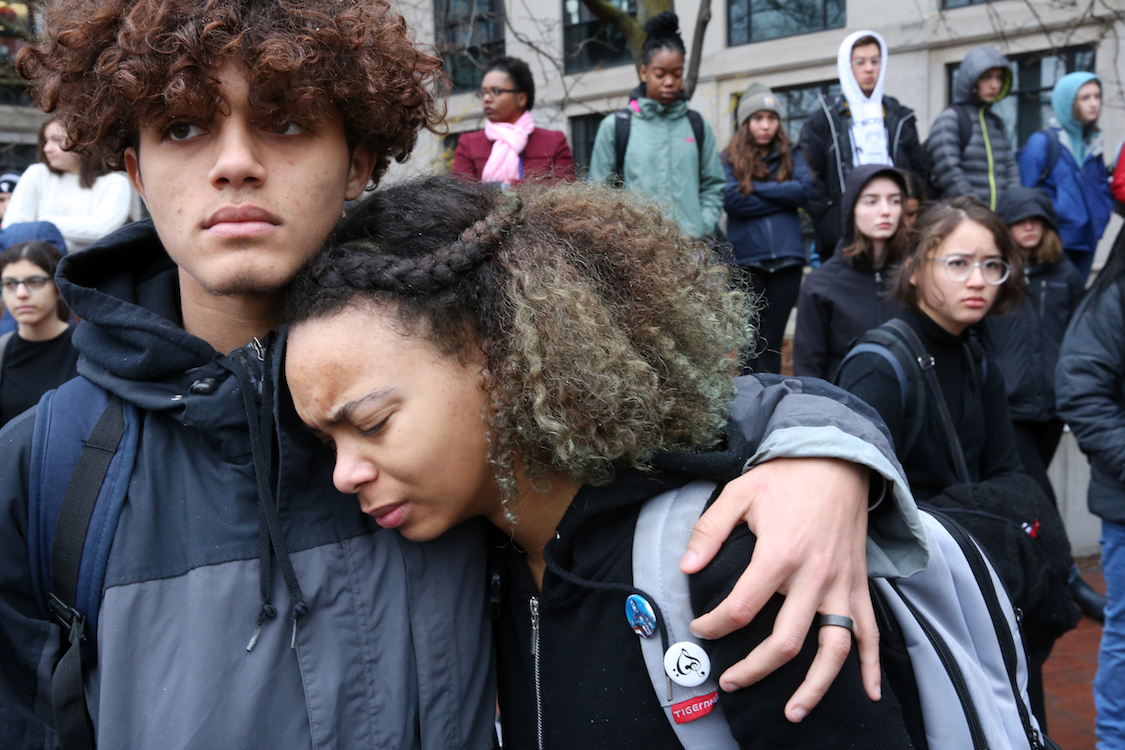 Junior Nigel Wallace comforts freshman Aleyana Pina during a student walkout to protest gun violence in schools and demand new gun control laws at Cambridge Rindge and Latin School in Cambridge, MA. CREDIT: Craig F. Walker/The Boston Globe via Getty Images