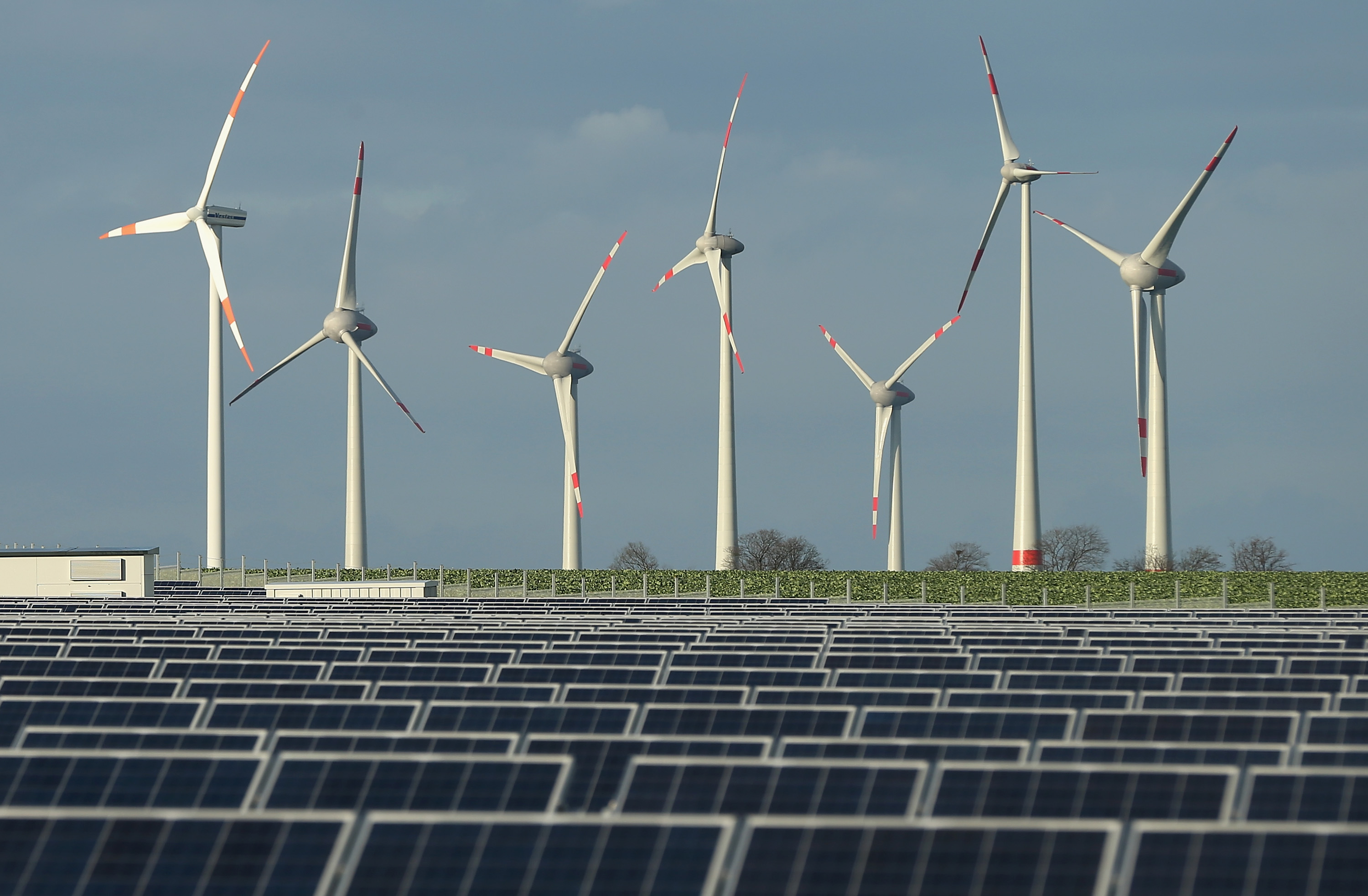 Wind turbines stand behind a solar power park on October 30, 2013 near Werder, Germany. (CREDIT: Sean Gallup/Getty Images)