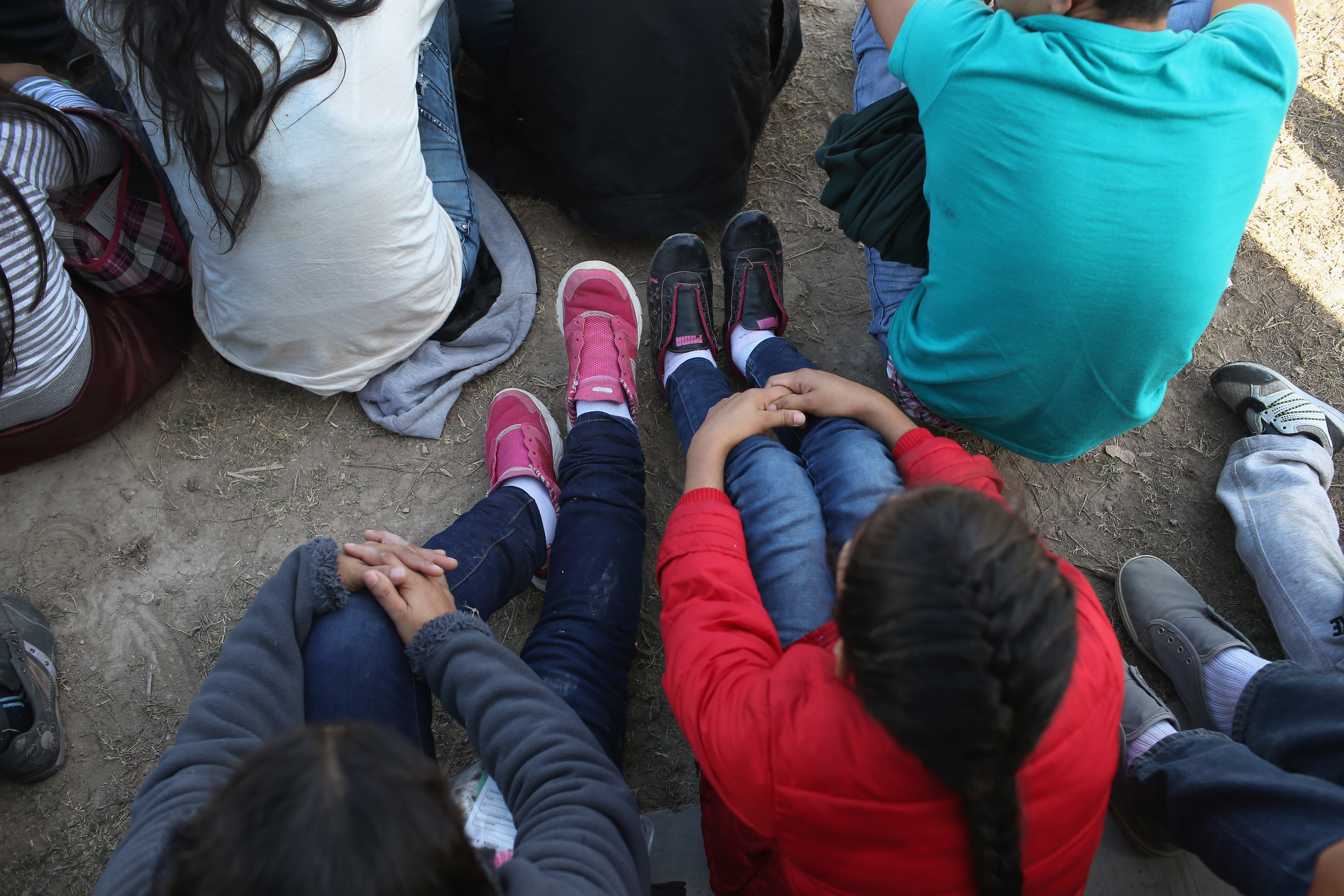 Central American immigrants sit after turning themselves in to U.S. Border Patrol agents on December 8, 2015 near Rio Grande City, Texas. (CREDIT: John Moore/Getty Images)