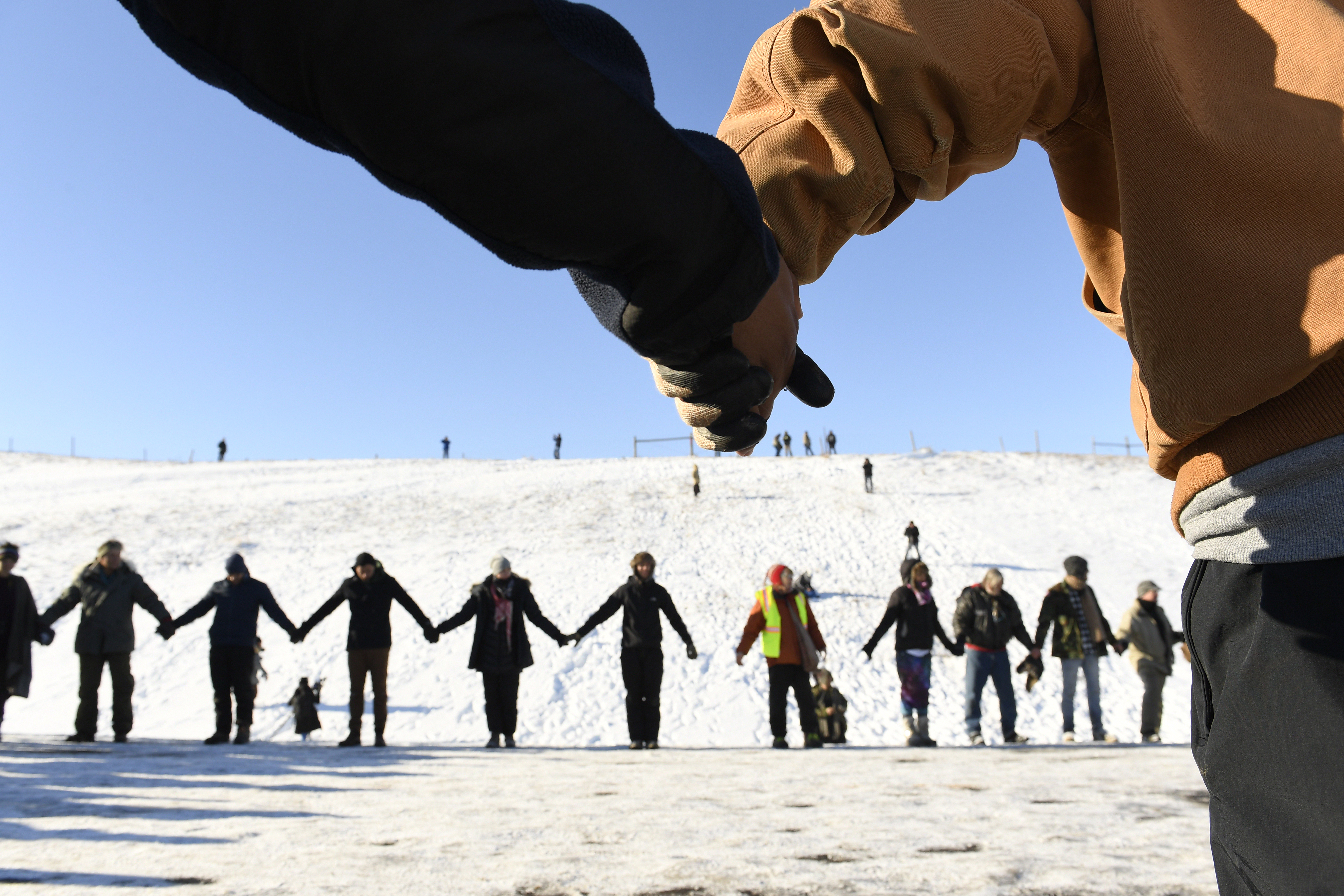 US veterans and Native Americans hold hands in prayer and solidarity on the road near Oceti Sakowin Camp on the edge of the Standing Rock Sioux Reservation on December 4, 2016 outside Cannon Ball, North Dakota. (CREDIT: Helen H. Richardson/The Denver Post via Getty Images)