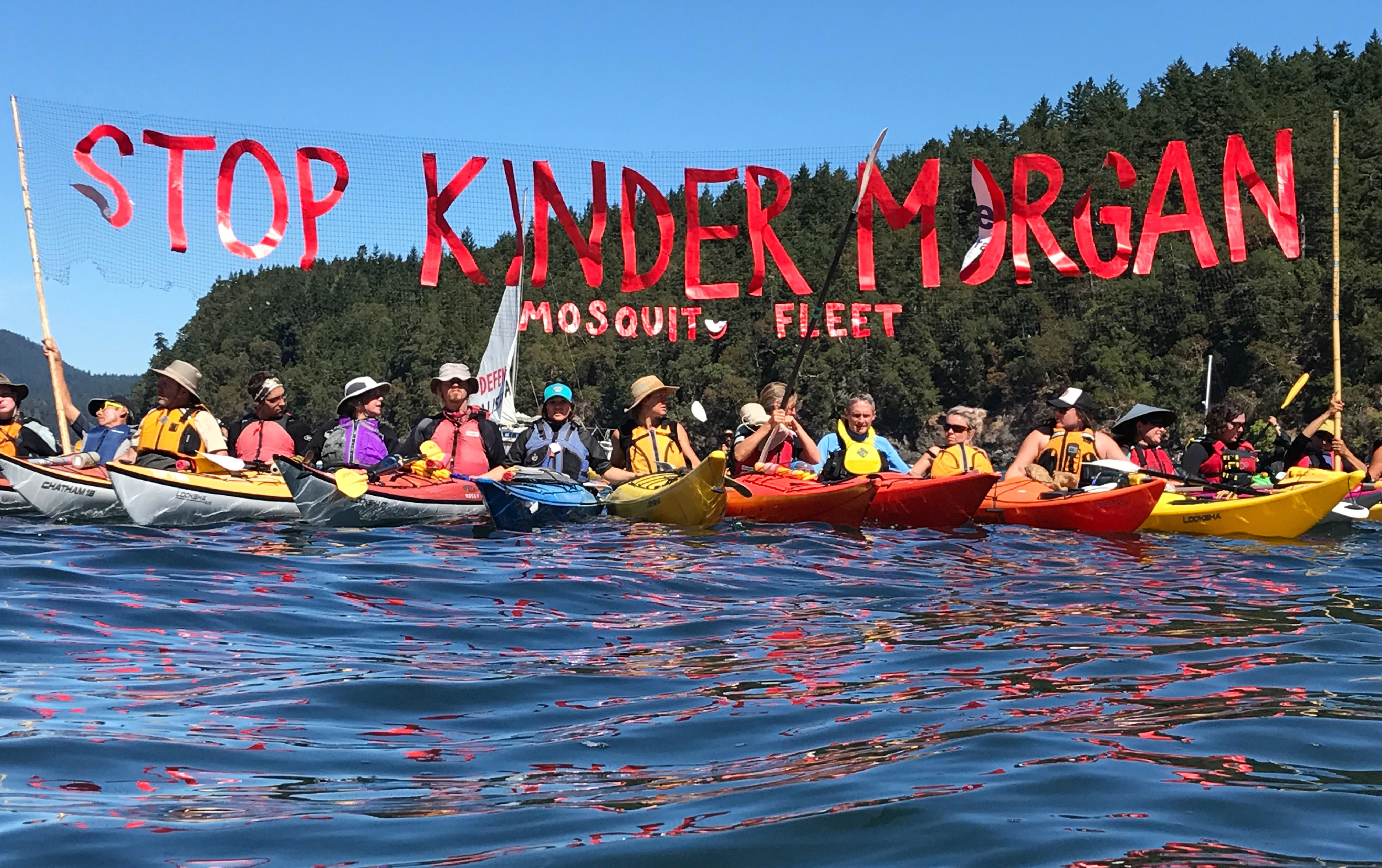 'Kayaktivists' hold up banner protesting plans by Kinder Morgan to build a pipeline during a water-based "pipeline resistance training camp", held by Greenpeace and the Mosquito Fleet in the San Juan Islands, in the waters just off the US-Canada border on August 26, 2017.
(CREDIT: TIM EXTON/AFP/Getty Images)