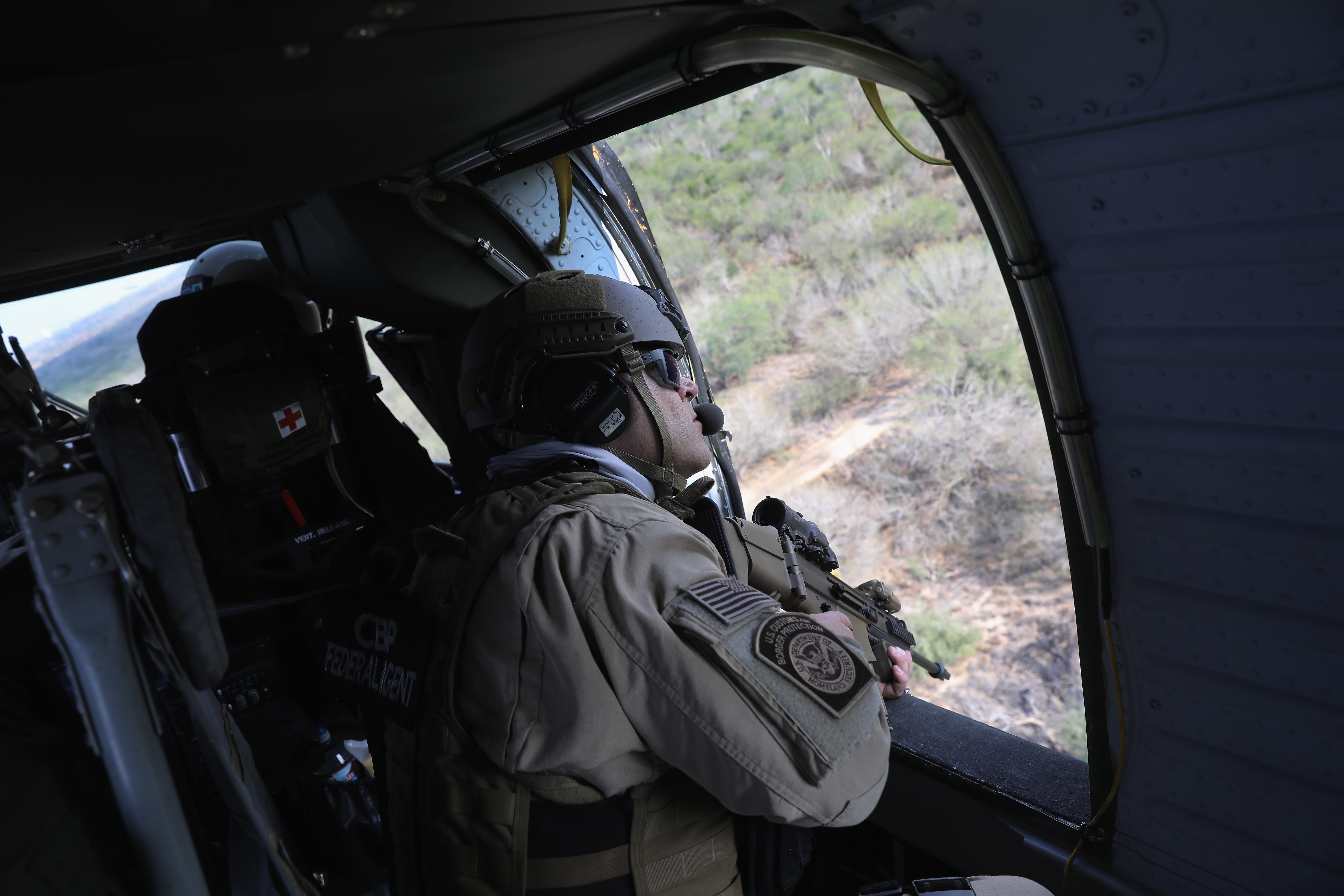 A U.S. Customs and Border Protection (CBP) agent flies in a Black Hawk helicopter while pursuing a truck with suspected undocumented immigrants on February 21, 2018 in McAllen, Texas. (CREDIT: John Moore/Getty Images)