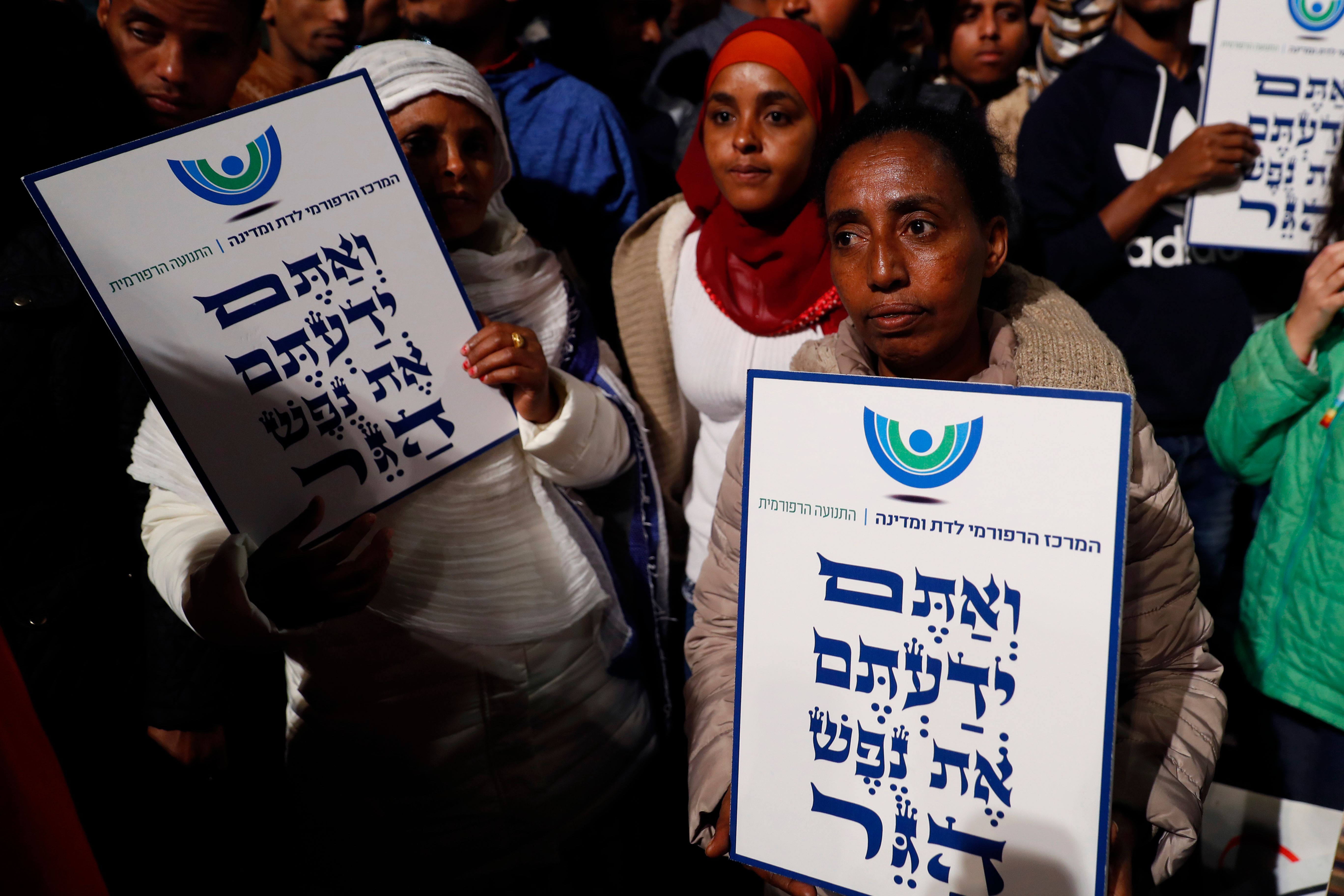 African migrants hold signs reading in Hebrew "You come from the Bible, you too are refugees", during a demonstration in the Israeli coastal city of Tel Aviv on February 24, 2018, against the Israeli government's policy to forcibly deport African refugees and asylum seekers to Rwanda and Uganda. CREDIT: Jack Guez/AFP/Getty Images.