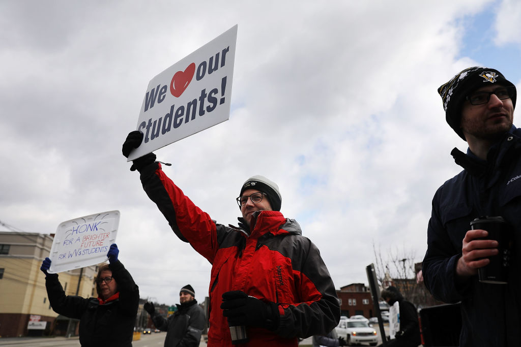 MORGANTOWN, WV - MARCH 02: West Virginia teachers, students and supporters hold signs on a Morgantown street as they continue their strike on March 2, 2018 in Morgantown, West Virginia. Despite a tentative deal reached Tuesday with the state's governor, teachers across West Virginia continued to strike on Friday as the Republican-controlled state legislature debated the governor's deal. (Photo by Spencer Platt/Getty Images)